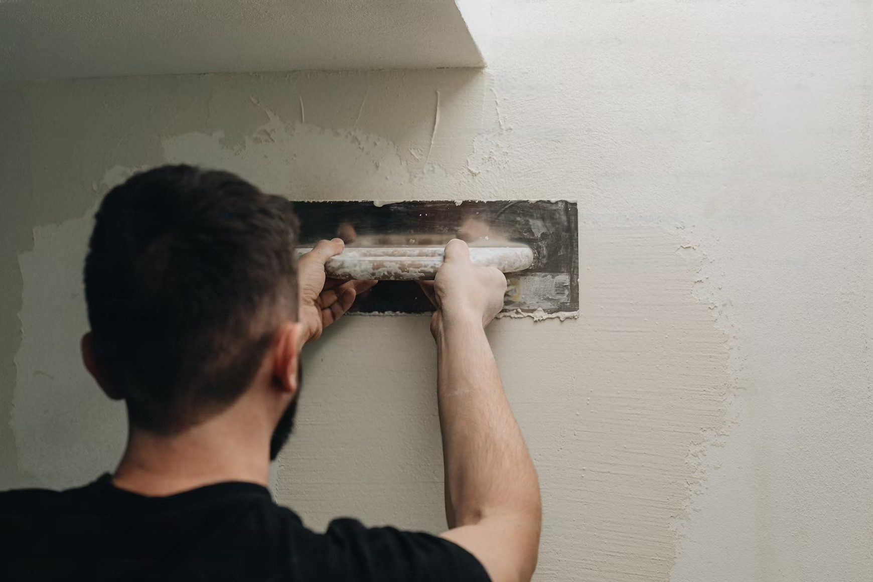 A man is plastering a wall with a spatula.