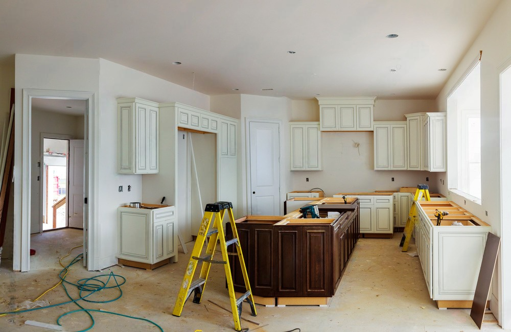 A kitchen is being remodeled in a house with a ladder in the middle of the room.