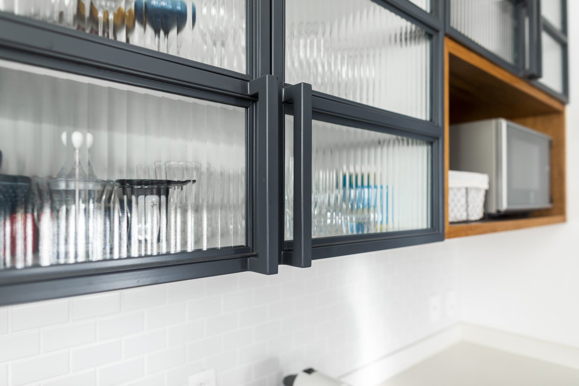 Uma cozinha com armários de vidro e micro-ondas.