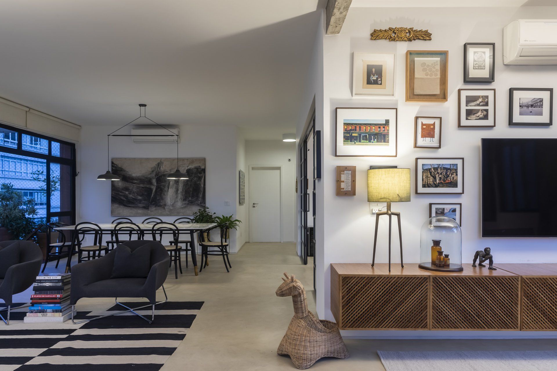 Uma sala com uma estátua de girafa no chão e uma televisão na parede.