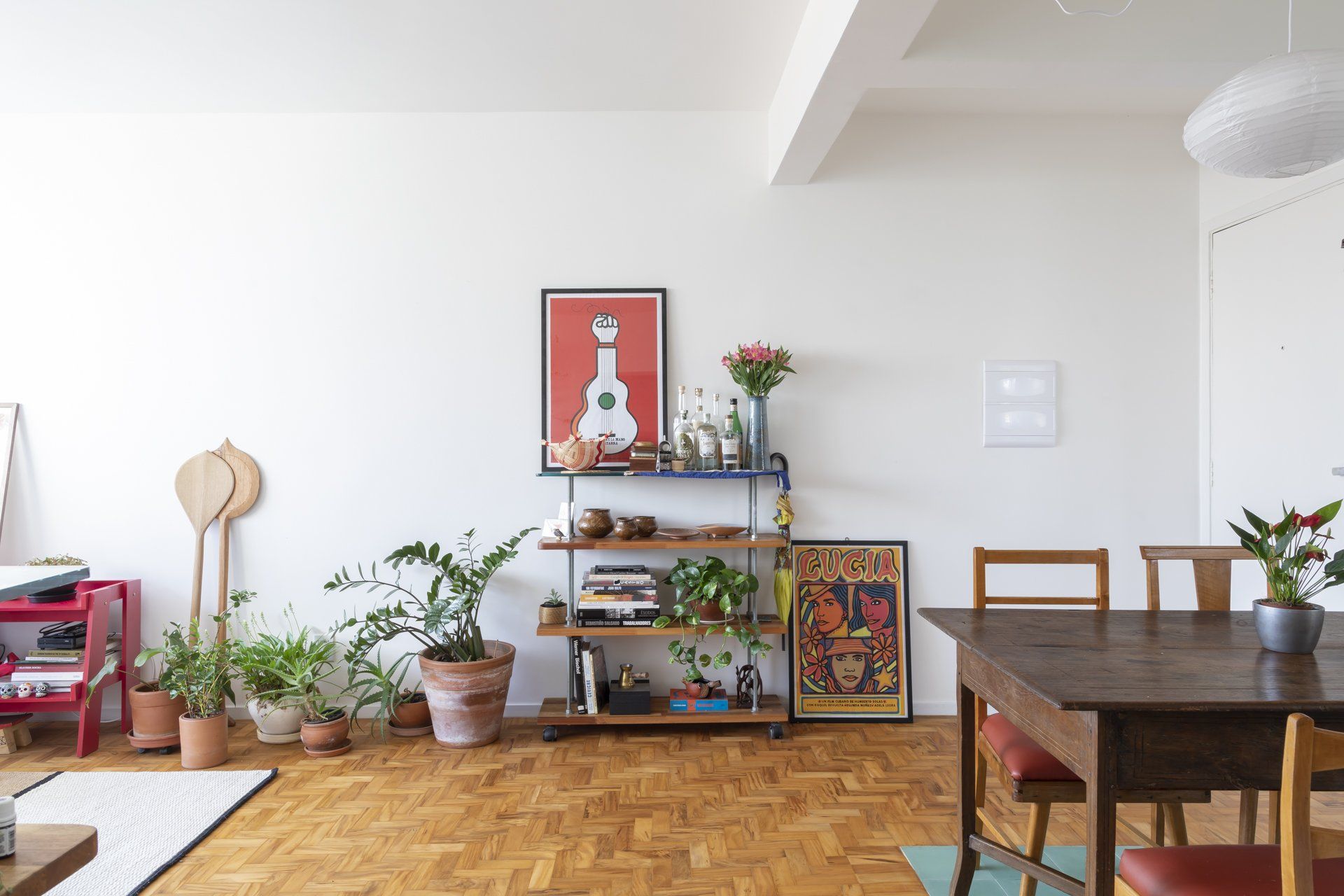 Uma sala de estar com mesa e cadeiras e uma estante com plantas.
