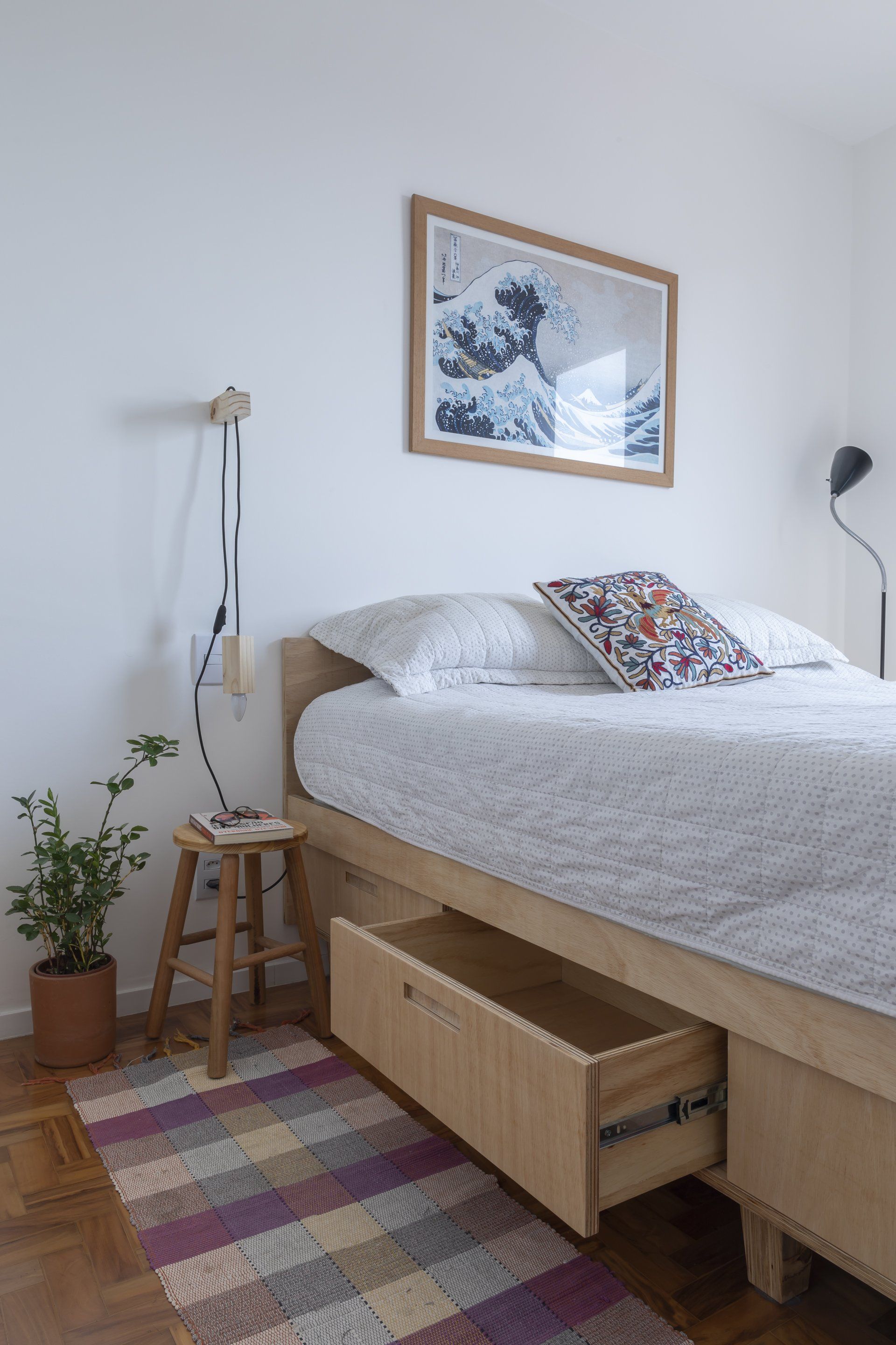 Uma cama com uma gaveta embaixo em um quarto.