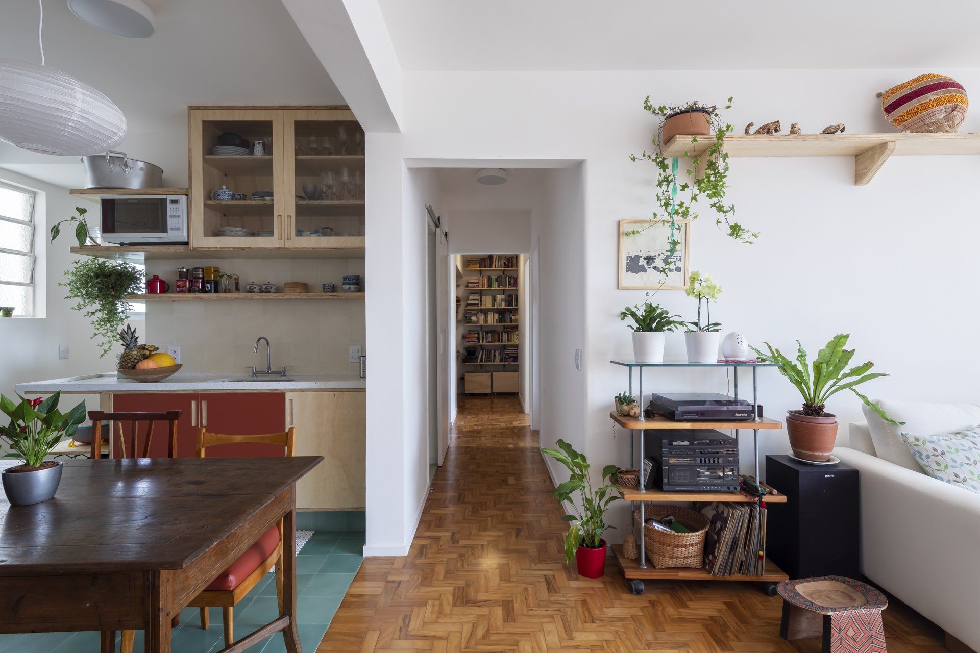 Uma sala de estar com mesa de madeira, cadeiras e plantas.