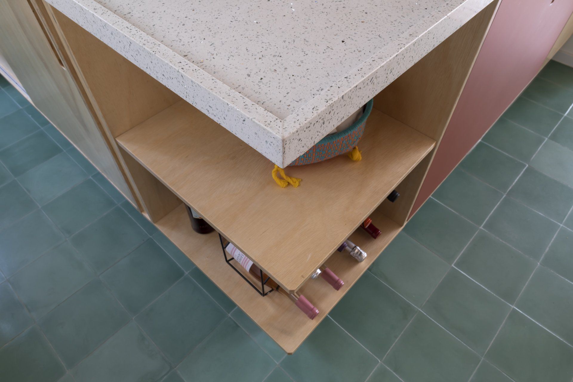 Uma prateleira de madeira com garrafas de vinho em uma cozinha.