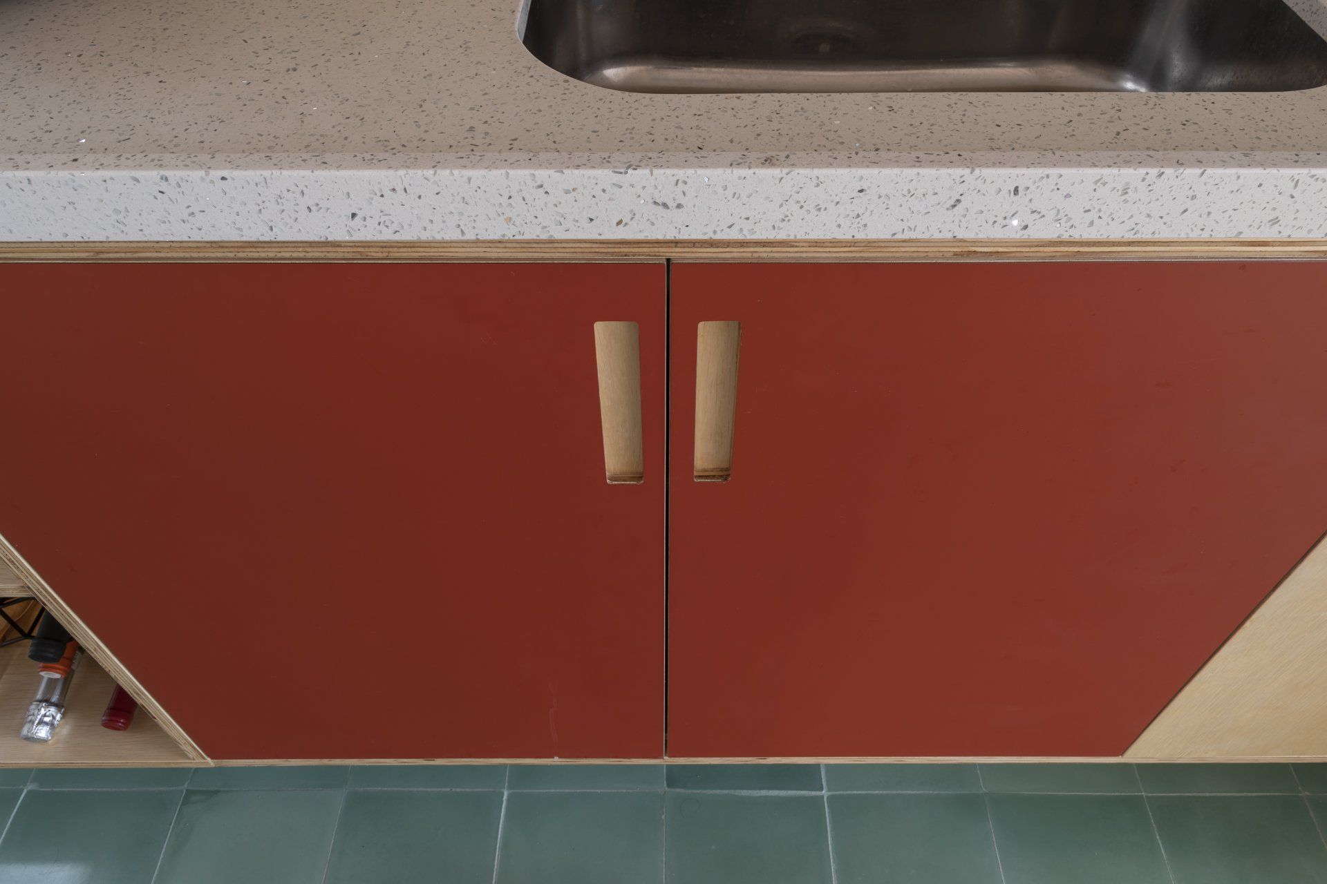 Uma cozinha com armários vermelhos e pia de aço inoxidável.