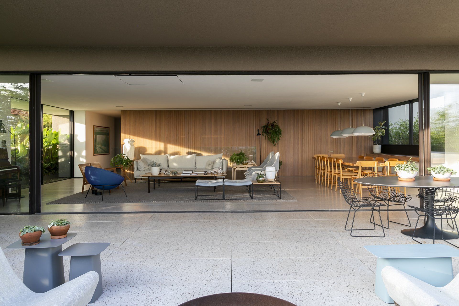 Uma sala de estar com muitos móveis e uma sala de jantar com mesa e cadeiras.