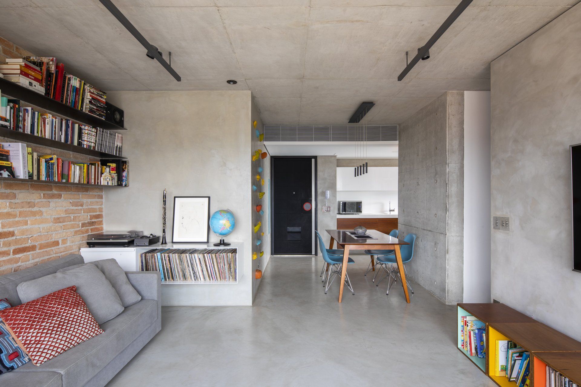 Uma sala com sofá, mesa, cadeiras e estantes.