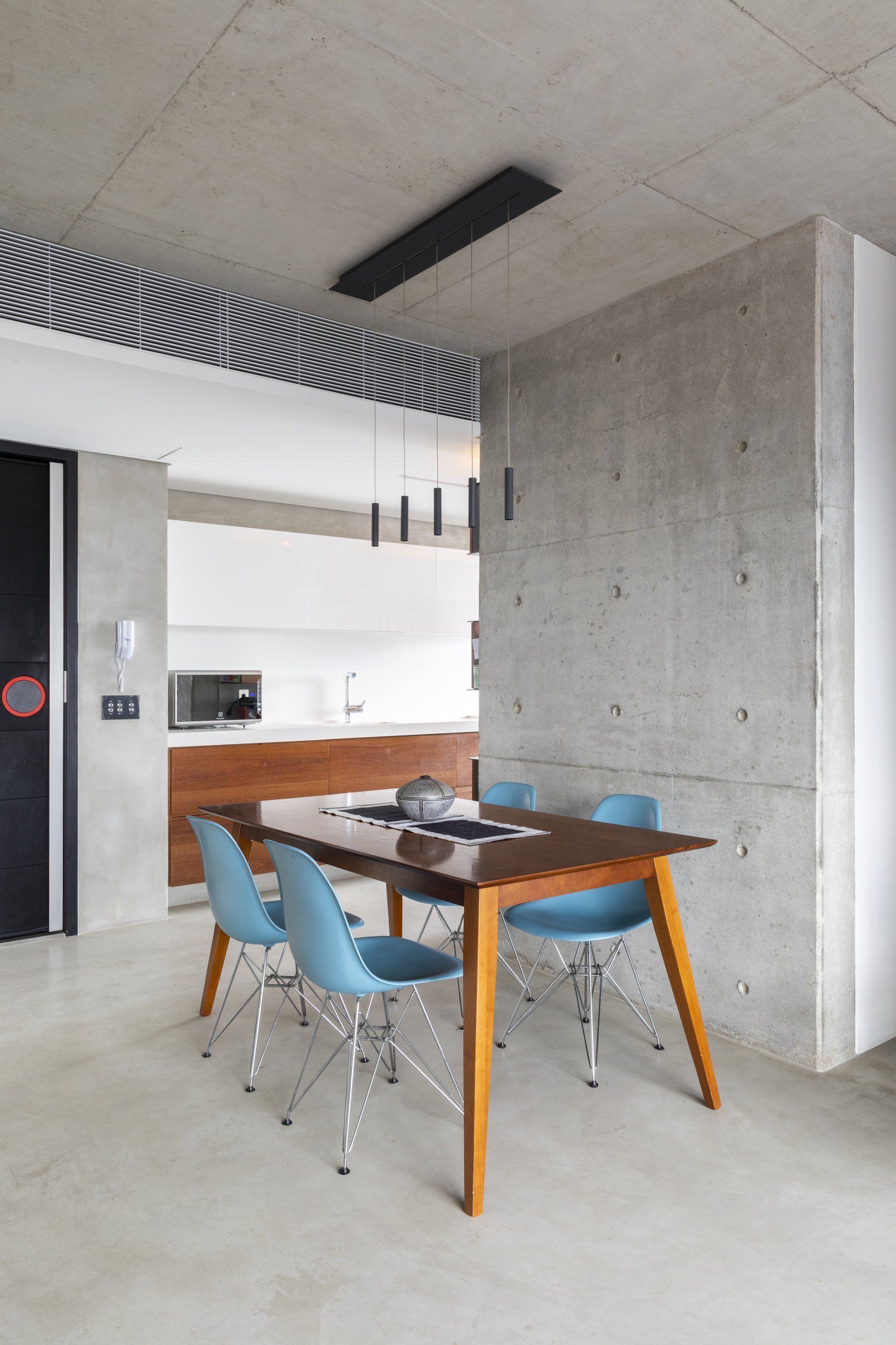 Uma sala de jantar com mesa e cadeiras e uma parede de concreto.