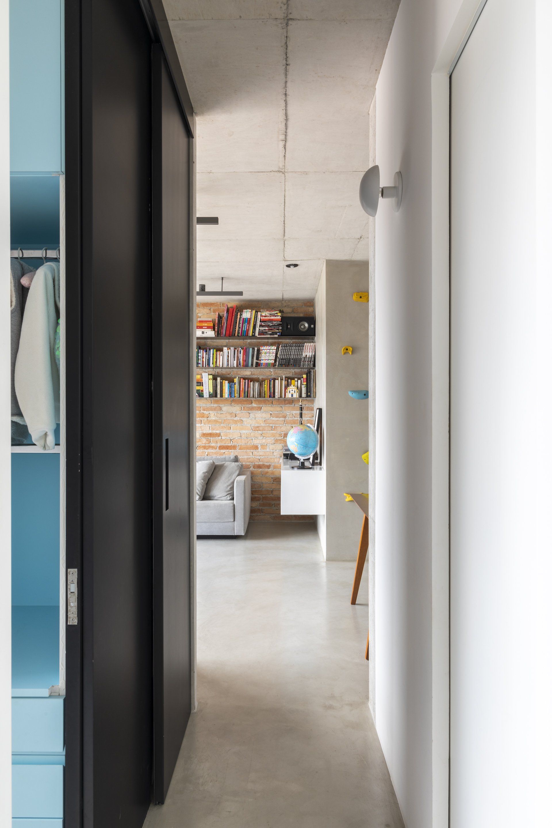 Um corredor com uma porta de correr que dá acesso a uma sala de estar.