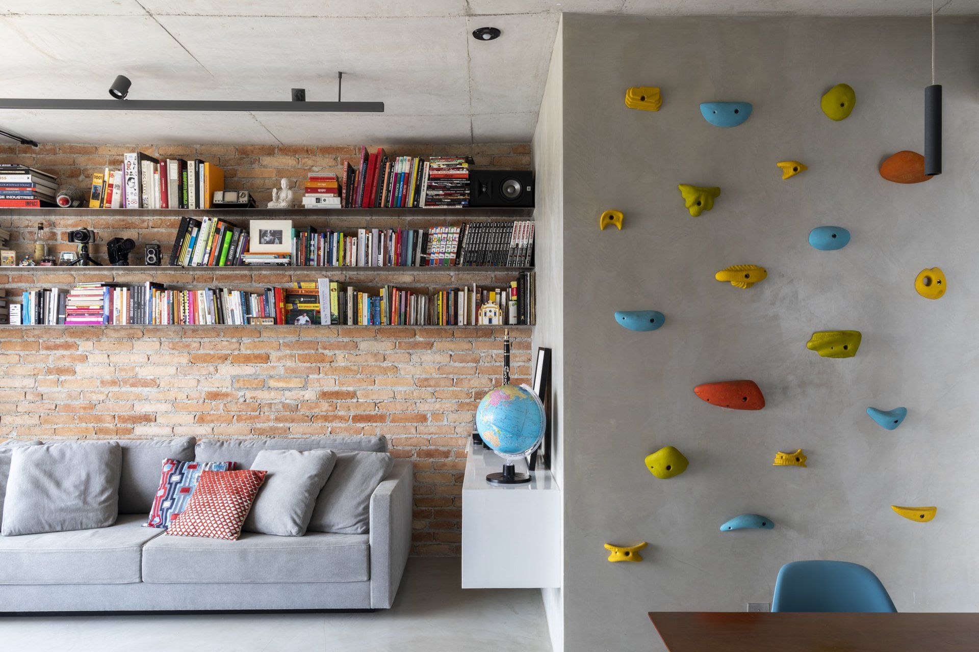 Uma sala com sofá e parede de escalada.