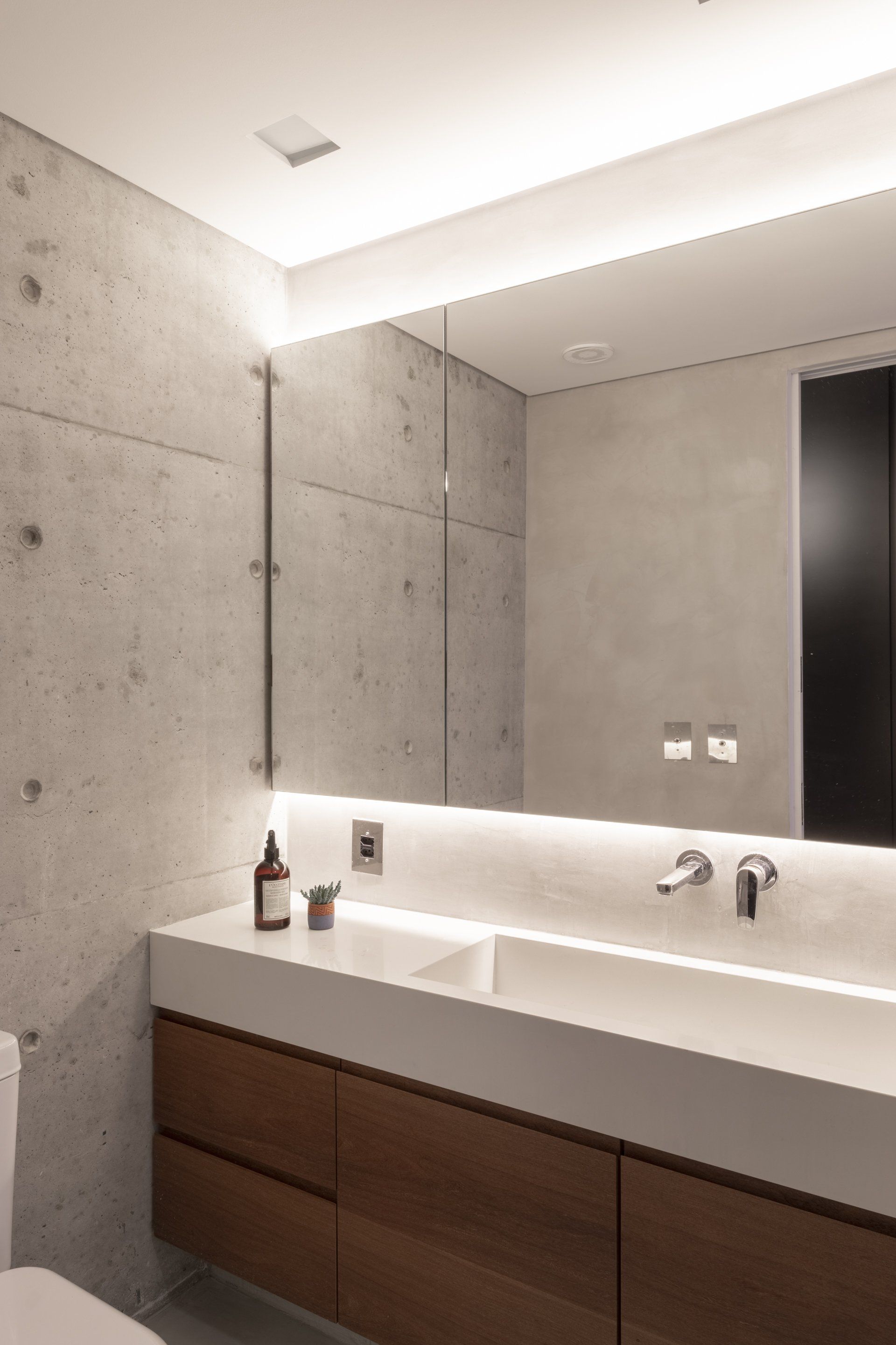 Um banheiro com pia, espelho e vaso sanitário.