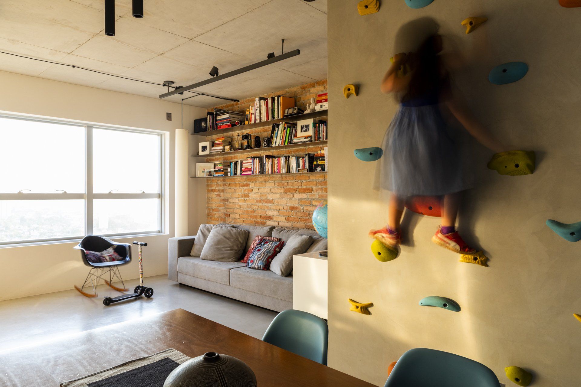 Uma menina está escalando uma parede de escalada em uma sala de estar.
