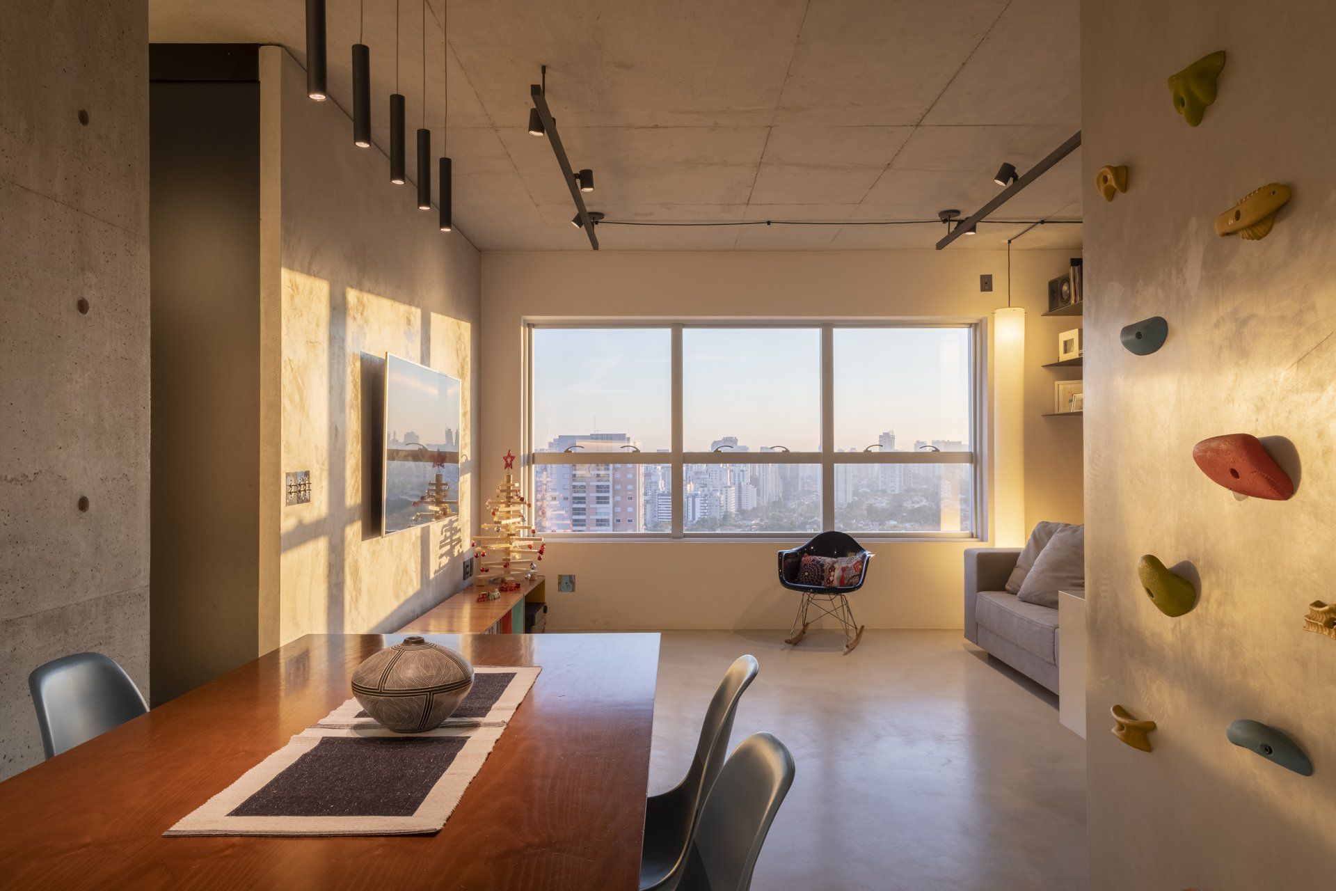 Uma sala de estar com mesa e cadeiras de jantar e parede de escalada.