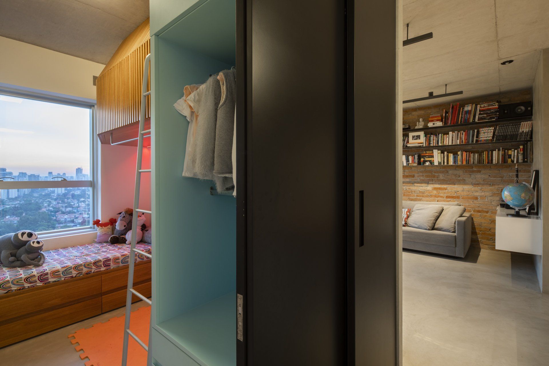 Um quarto com beliche e sofá ao lado de uma janela.