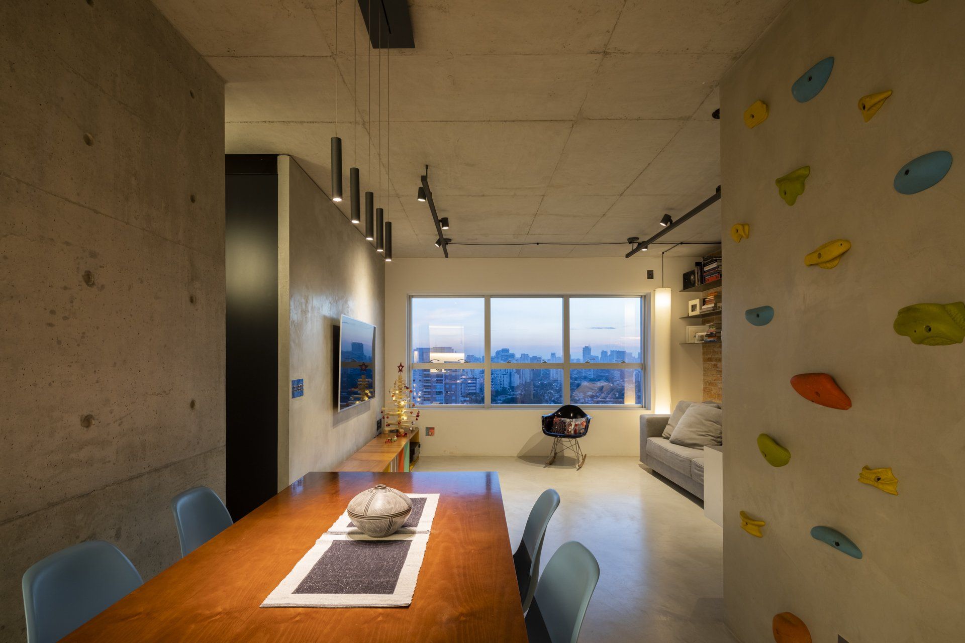 Uma sala de jantar com mesa e cadeiras de madeira e parede de escalada.
