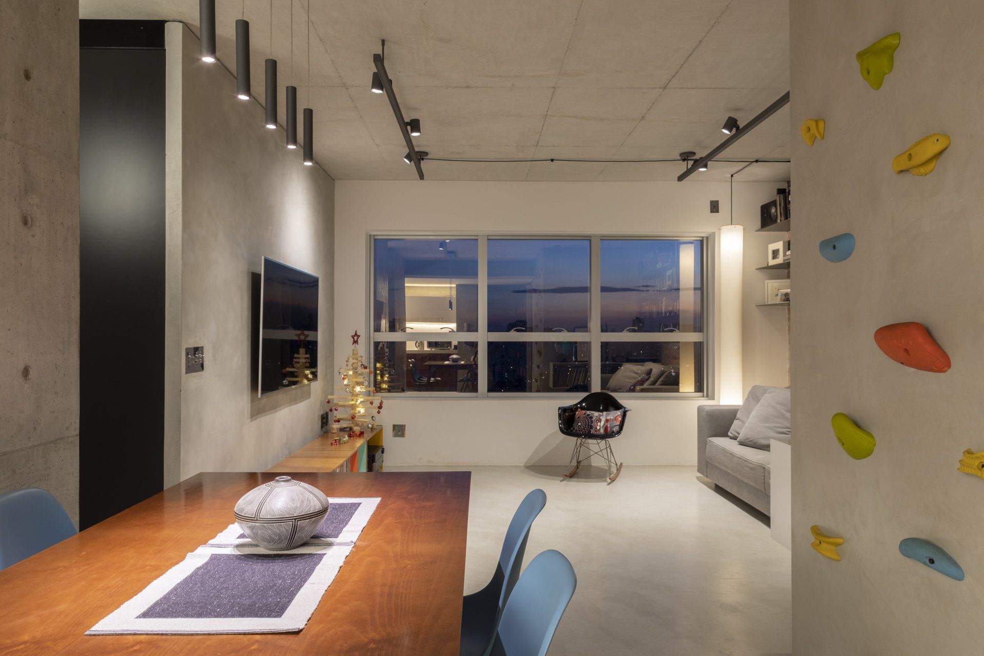 Uma sala de estar com mesa e cadeiras de jantar e parede de escalada.