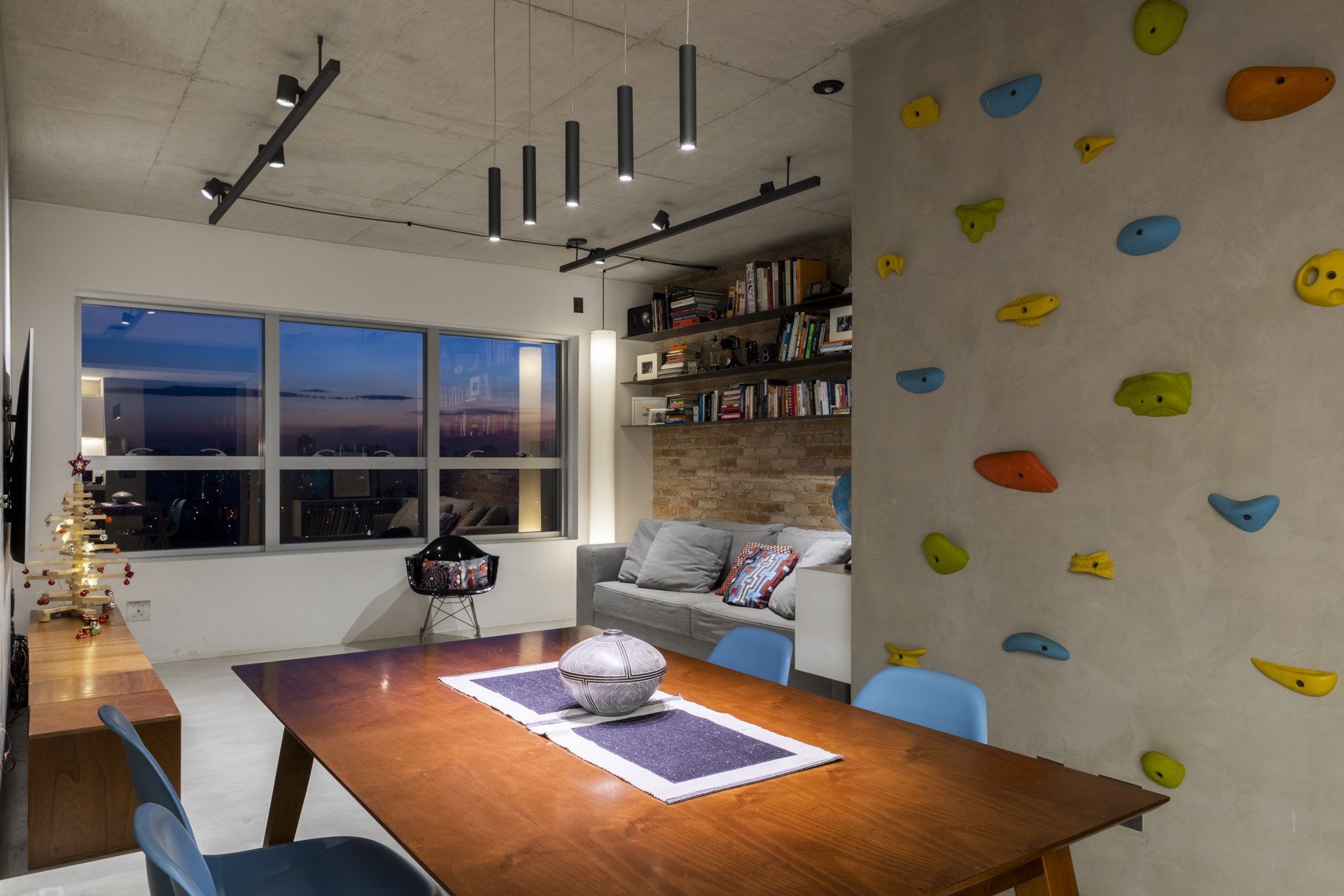Uma sala de jantar com mesa e cadeiras e parede de escalada.