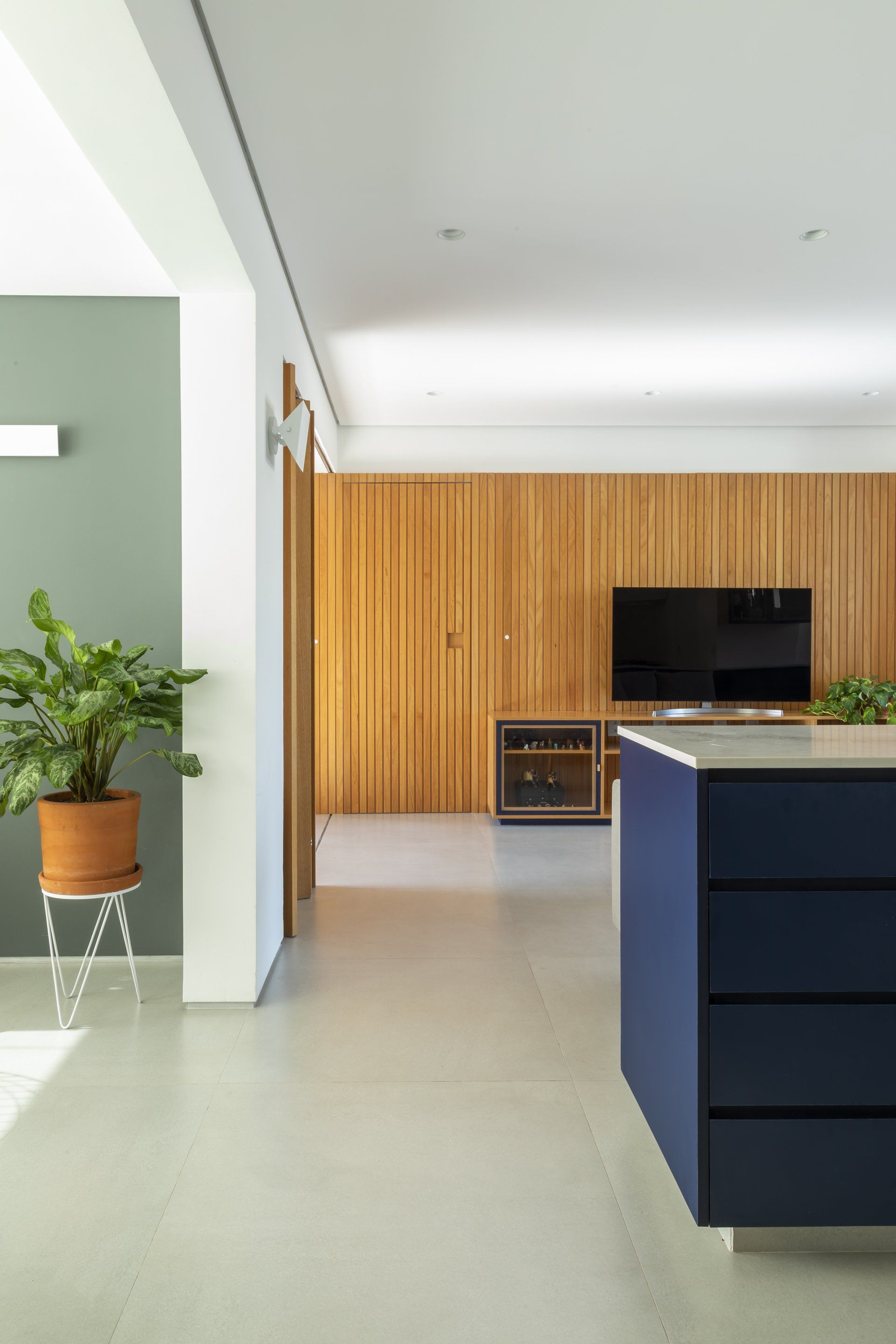 Uma cozinha com uma ilha azul, uma tv e um vaso de plantas.