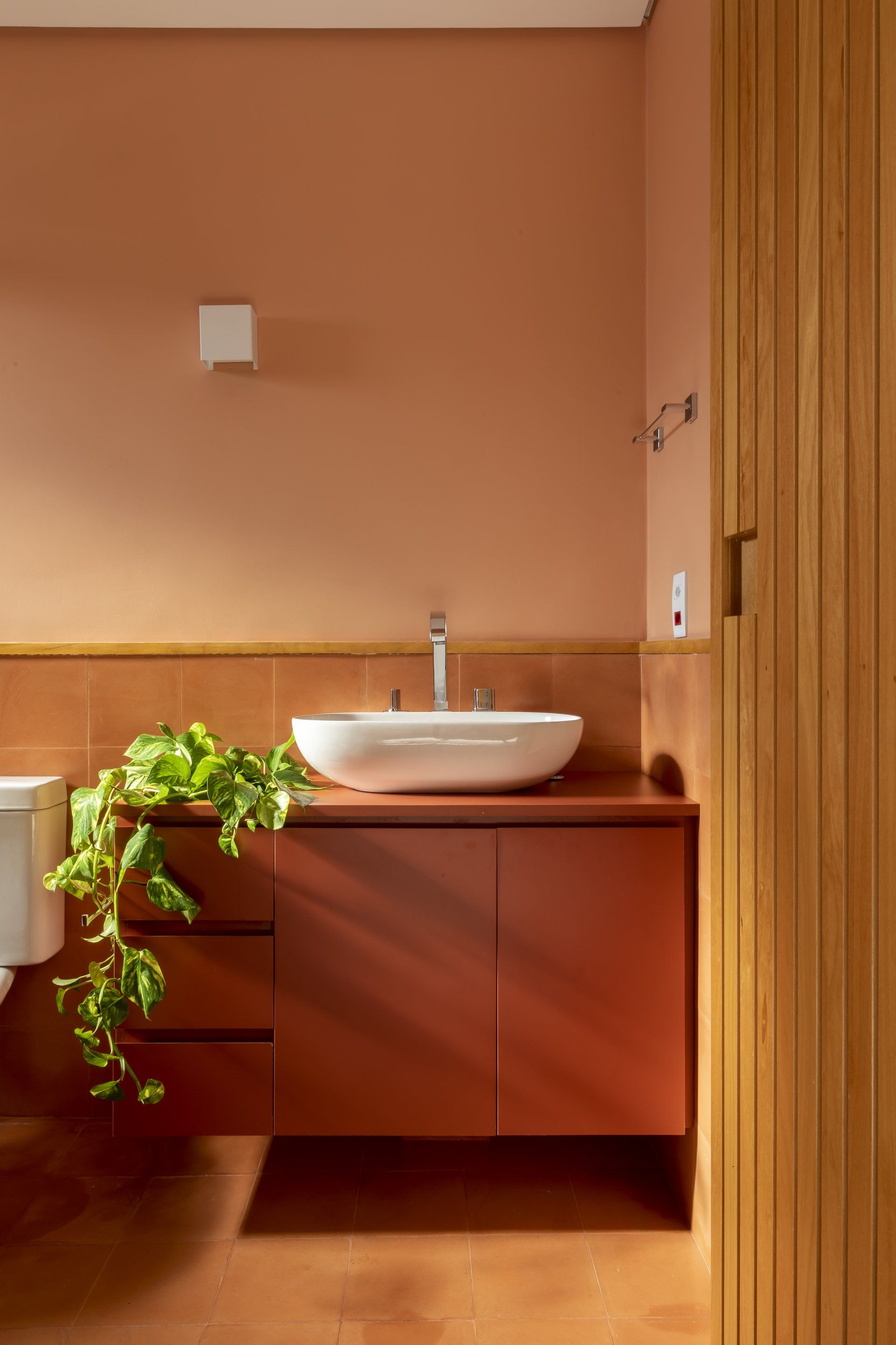 Um banheiro com pia, vaso sanitário e armários de madeira.