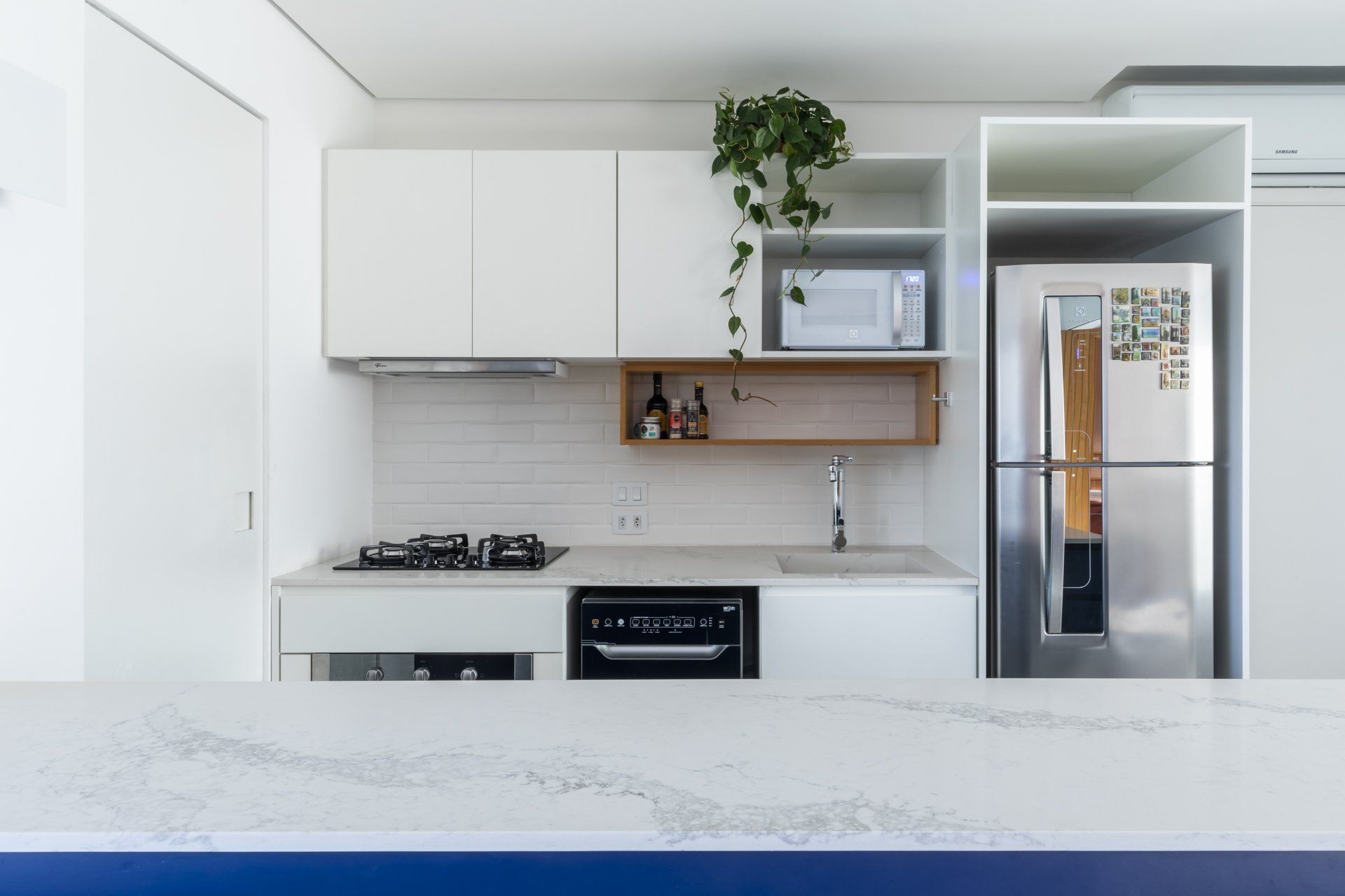 Uma cozinha com armários brancos e geladeira de aço inoxidável