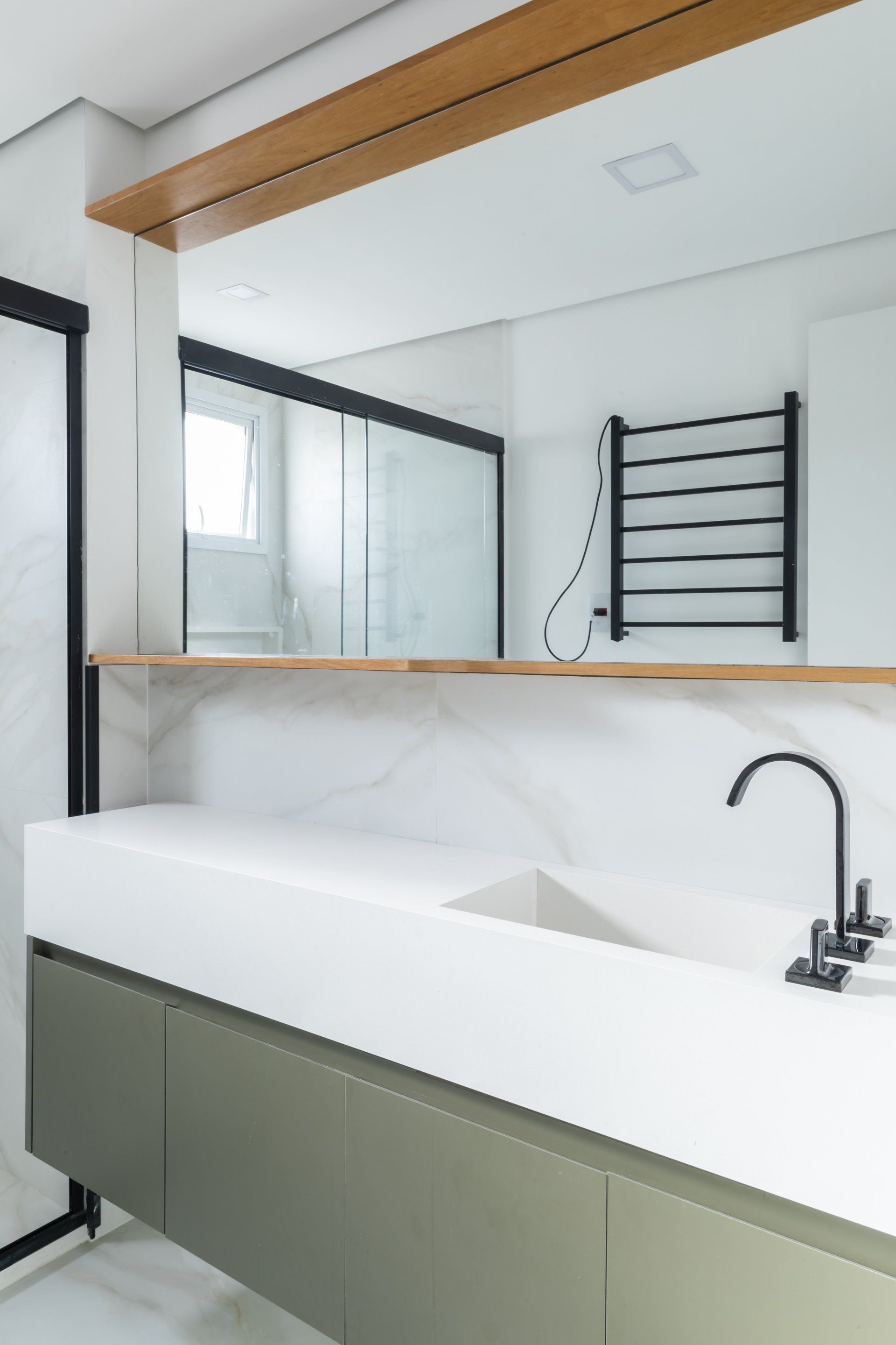 Um banheiro com pia, espelho e toalheiro.