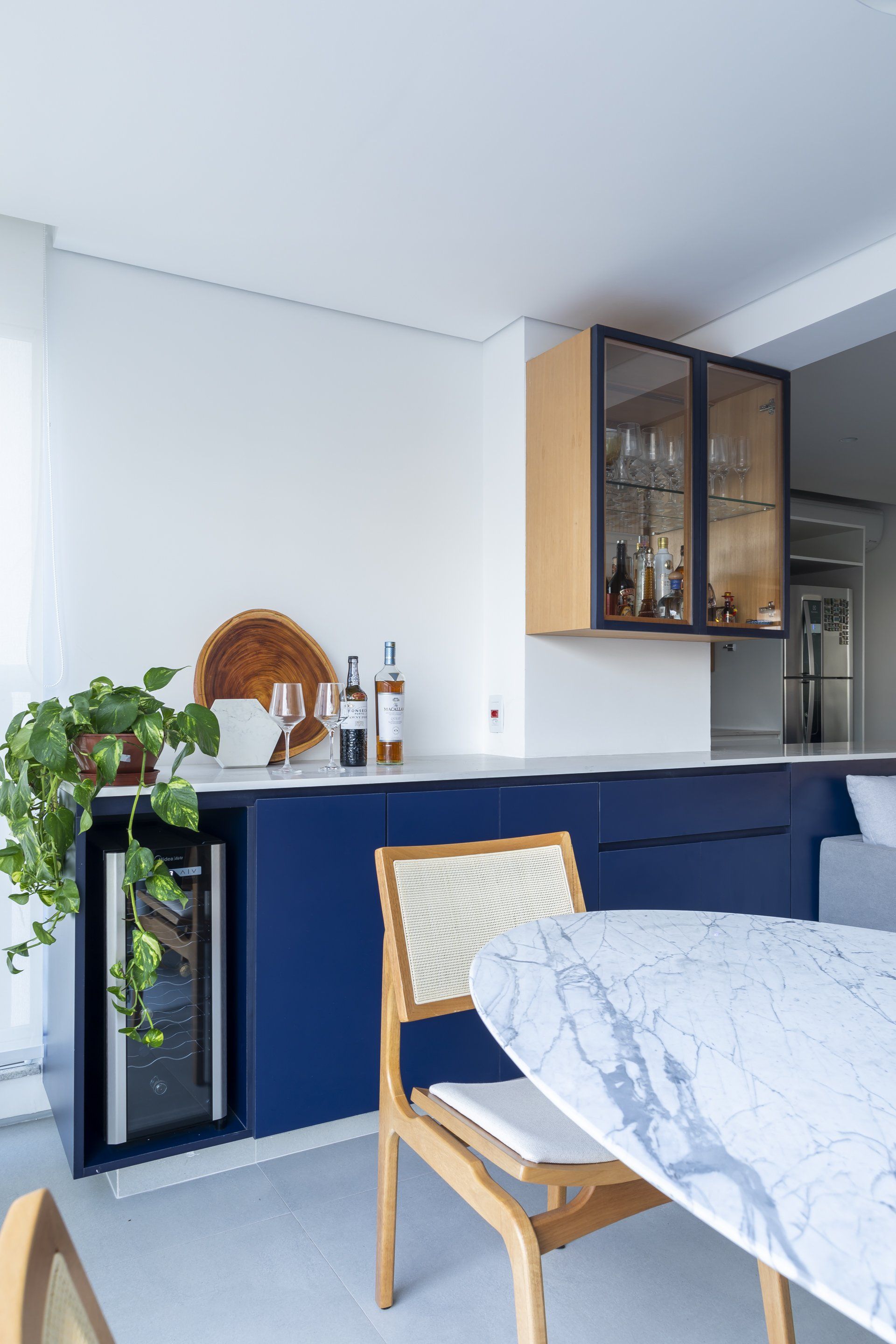 Uma sala de jantar com mesa, cadeiras e geladeira.