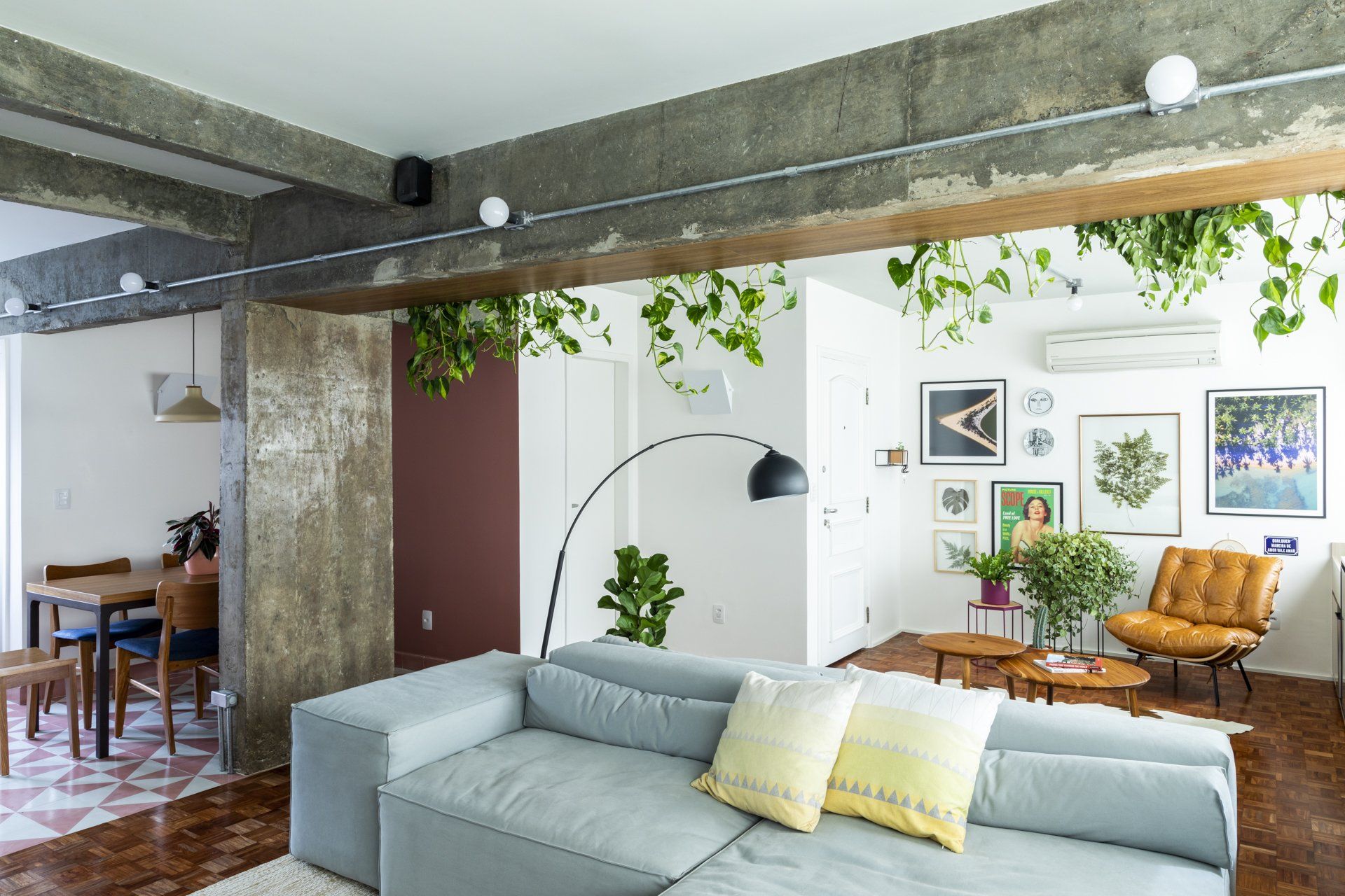 Uma sala com sofá, cadeiras, mesas e plantas penduradas no teto.