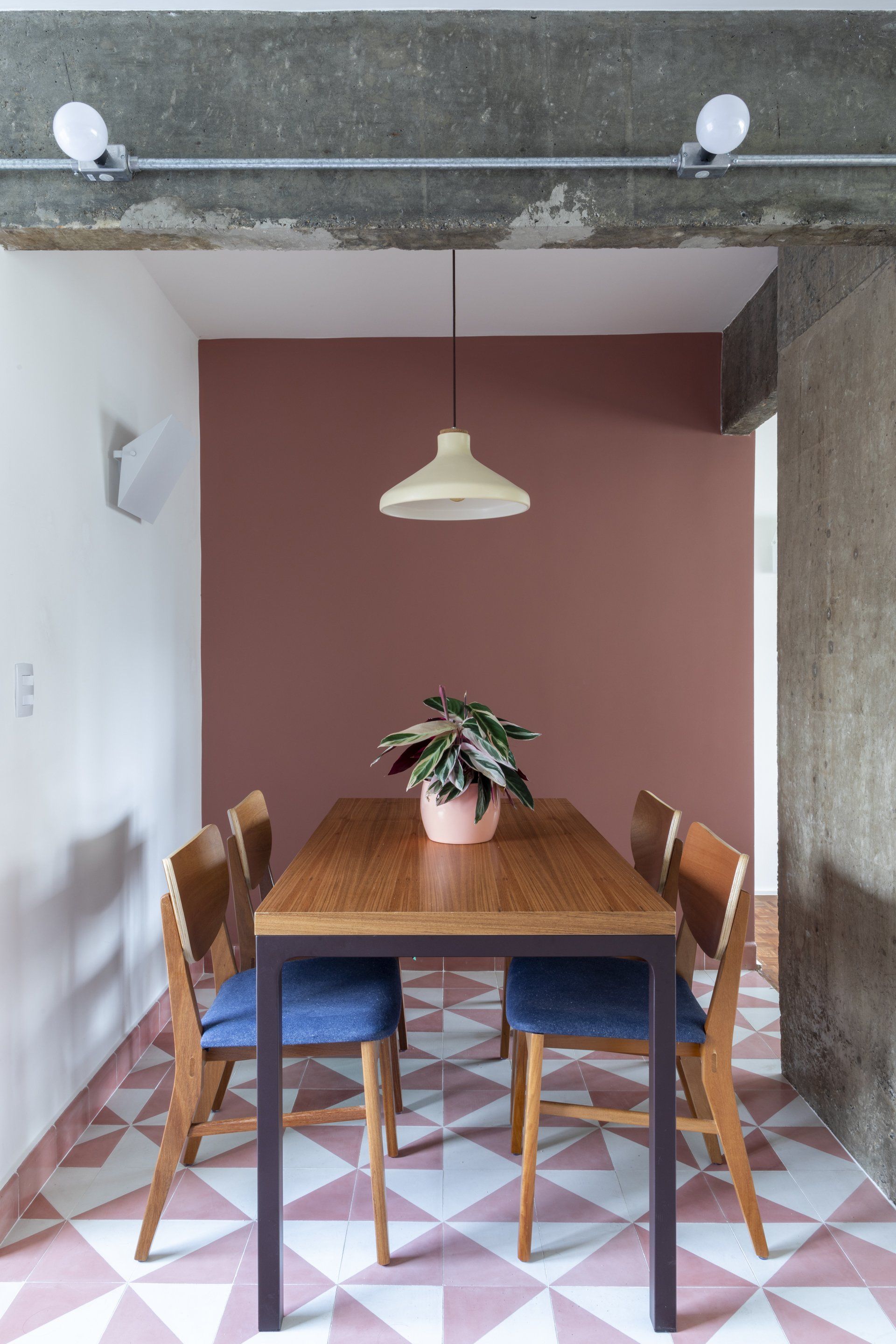 Uma sala de jantar com mesa e cadeiras e uma planta em cima da mesa.