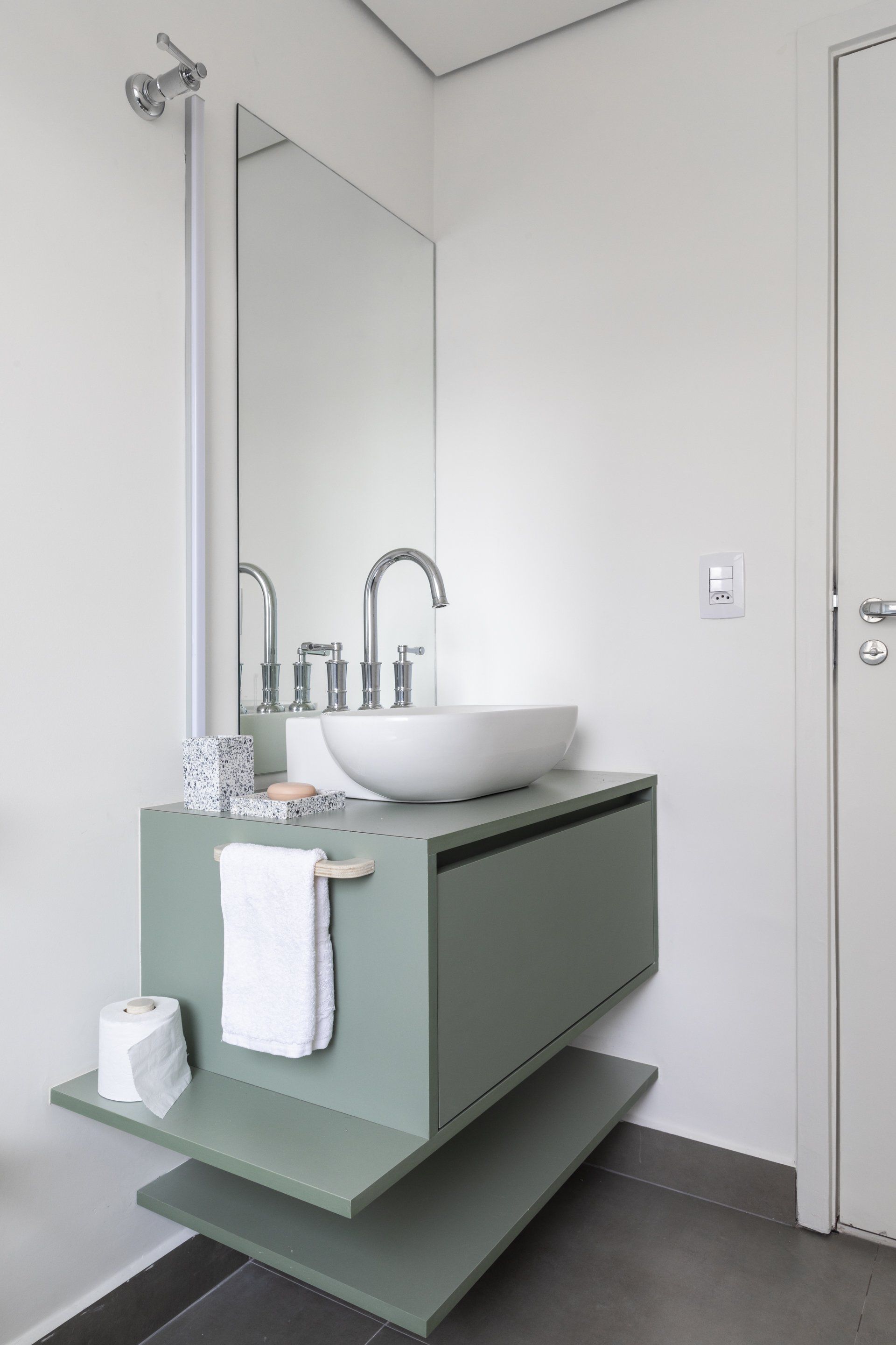 Um banheiro com pia, espelho e prateleira.