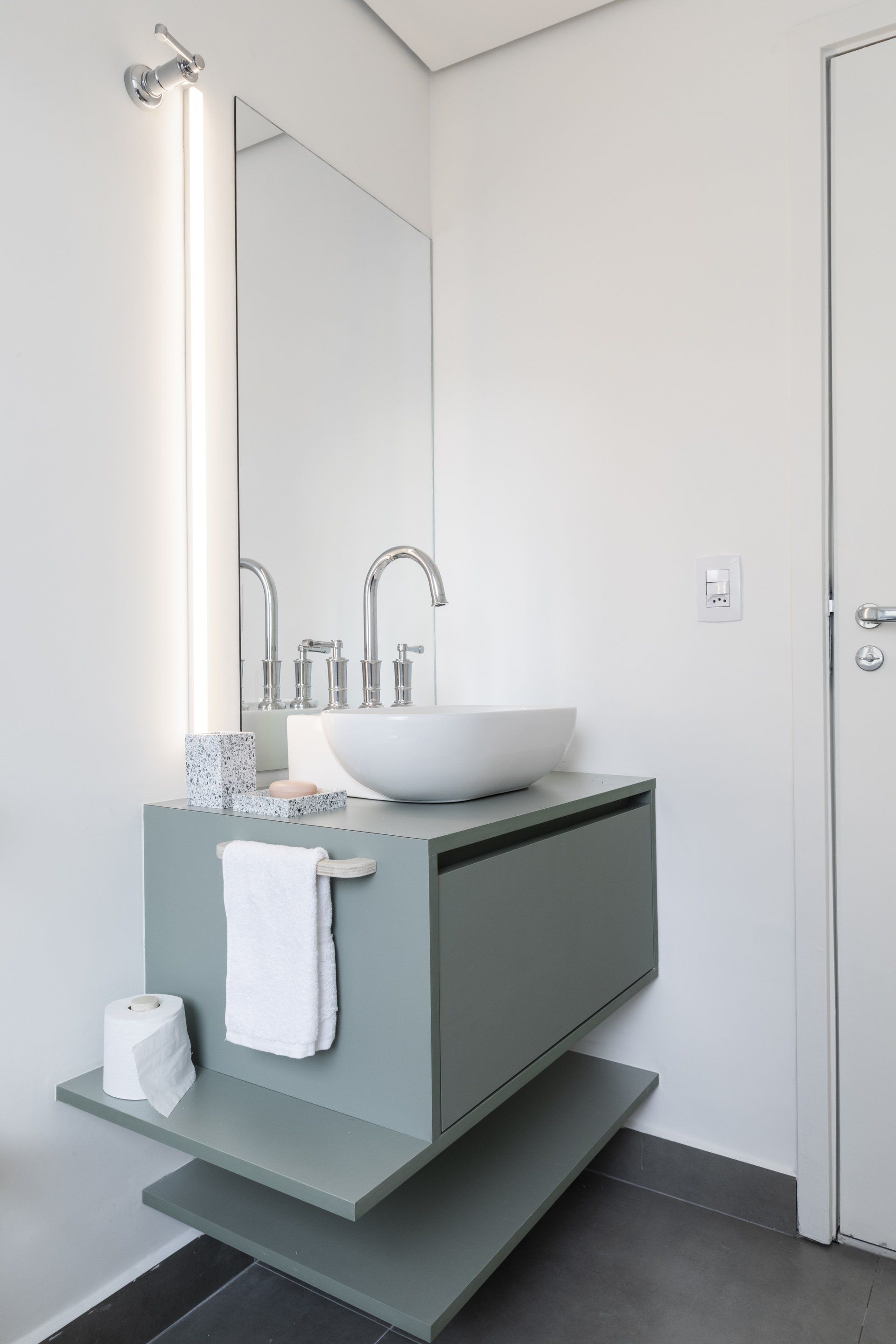 Um banheiro com pia, espelho e prateleira.