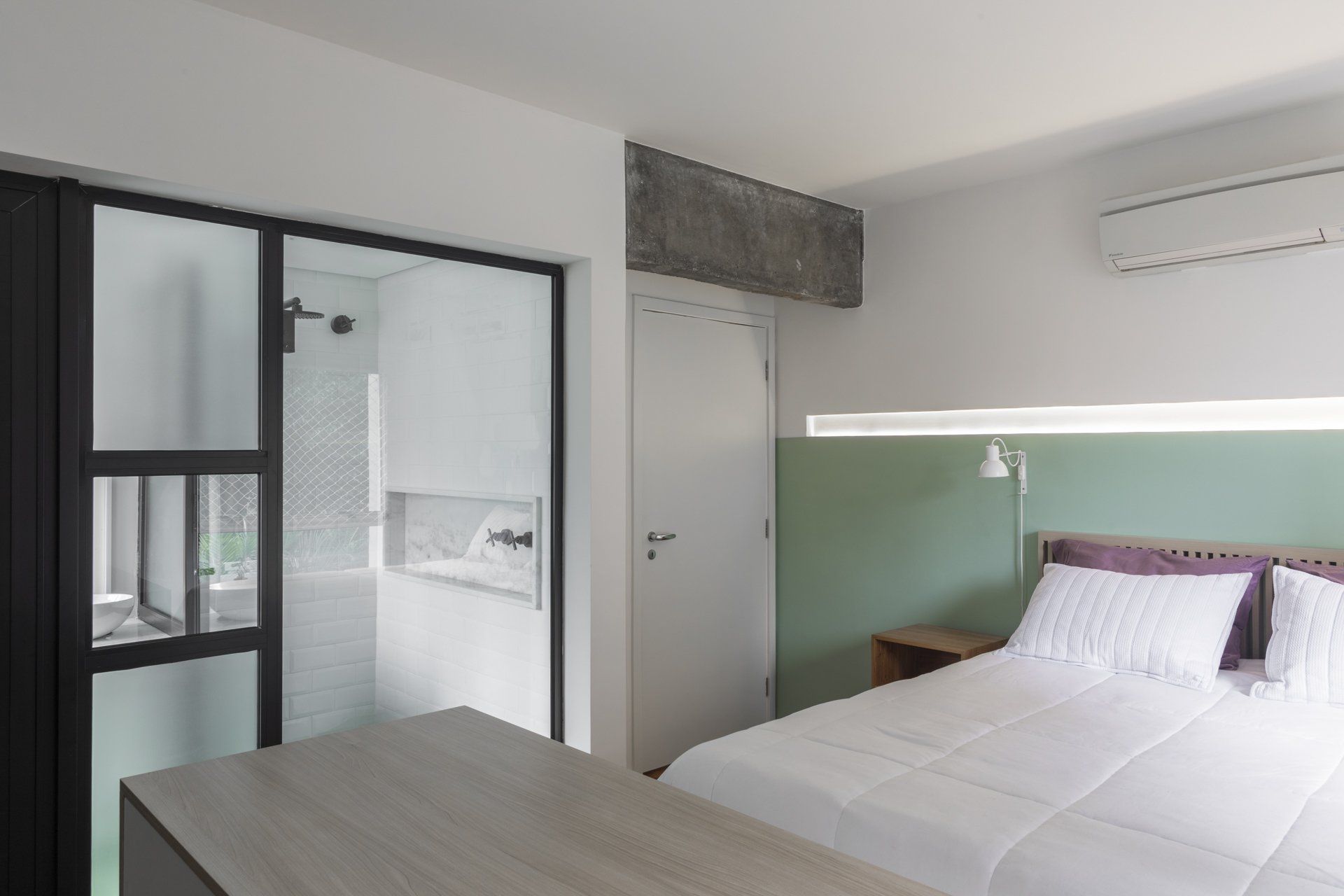 Um quarto com cama king size e porta de vidro que dá acesso ao banheiro.