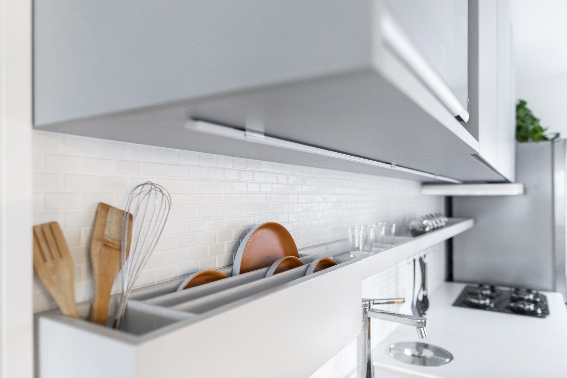 Uma cozinha com pia e uma prateleira com utensílios