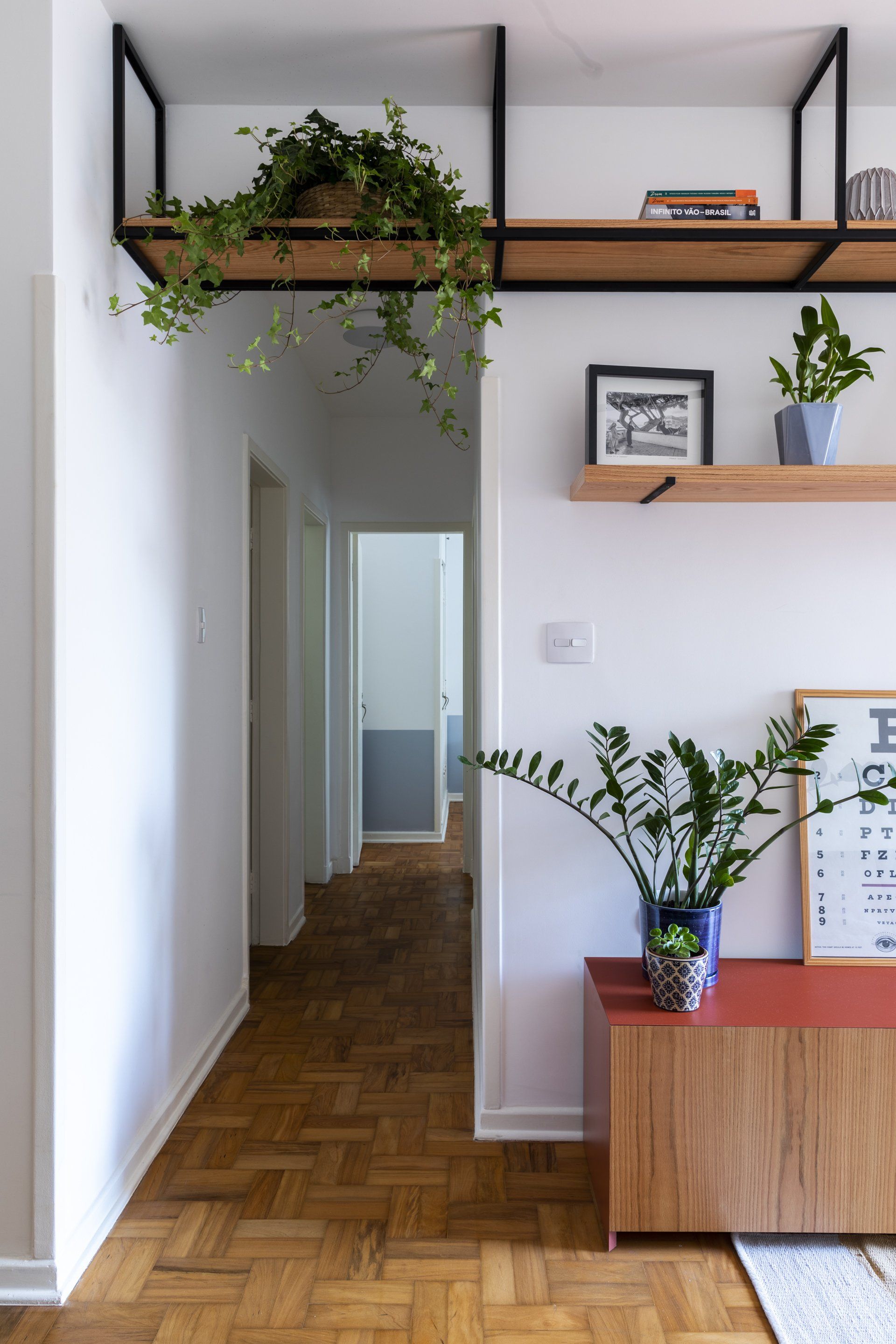 Um corredor com piso de madeira e uma prateleira com plantas