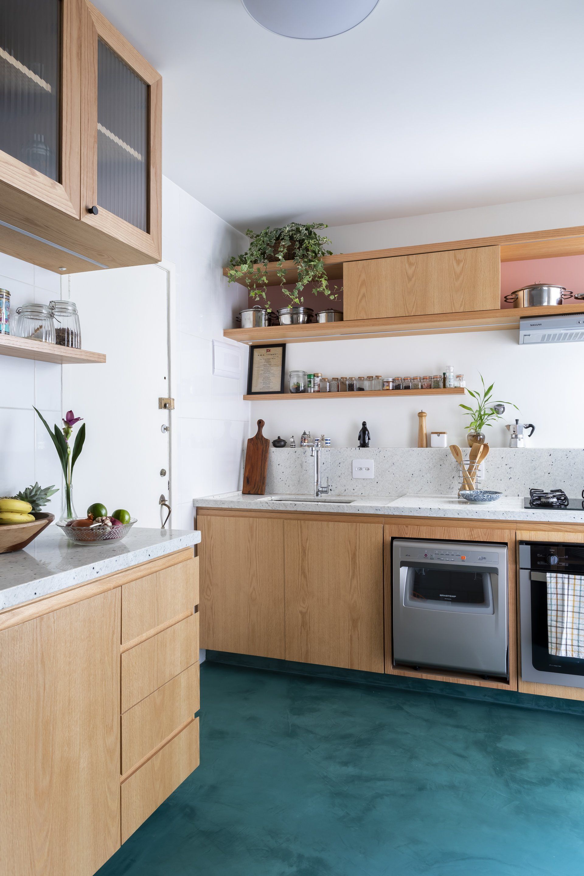 Uma cozinha com armários de madeira e piso verde.