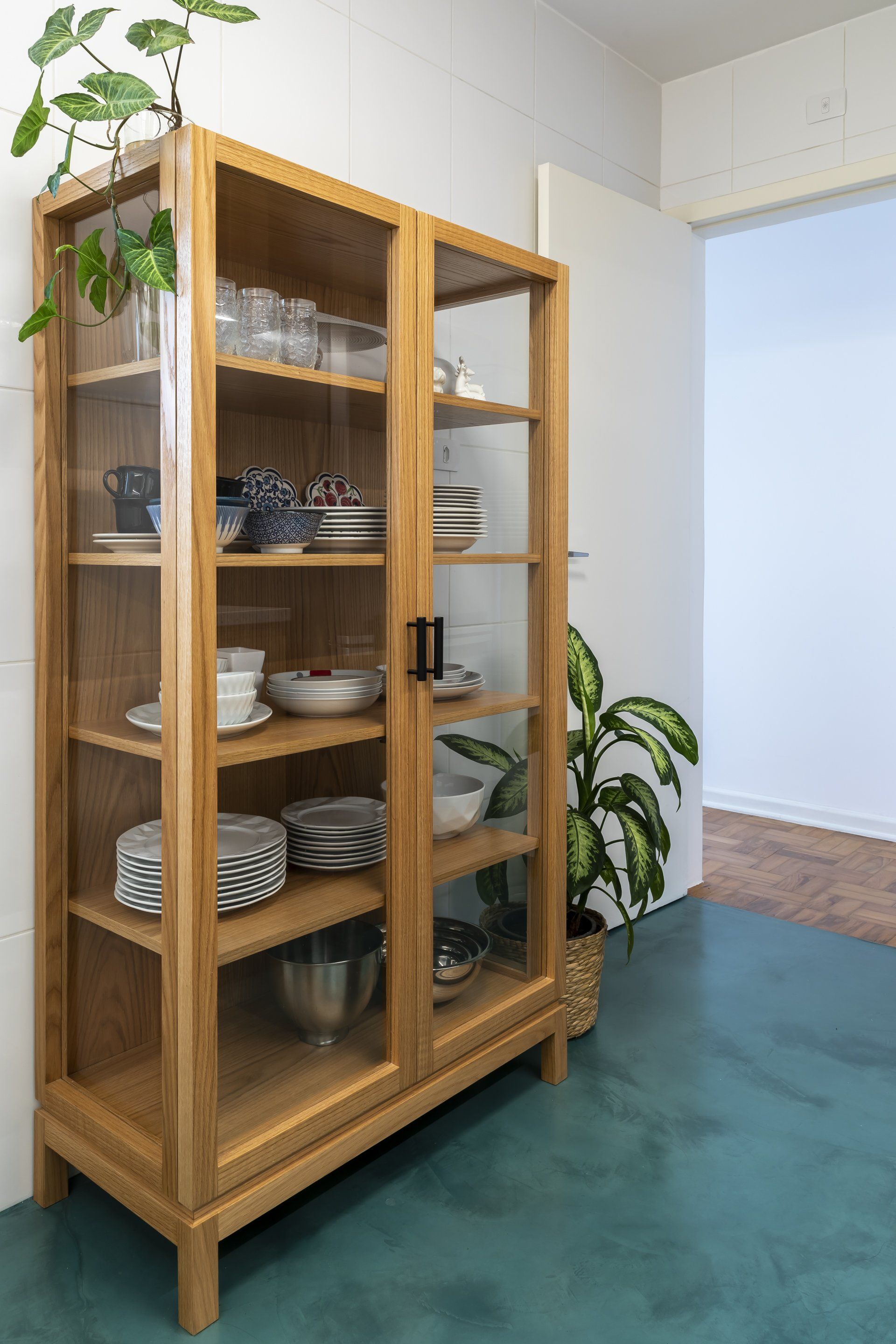 Um armário de madeira com portas de vidro cheio de pratos e tigelas.