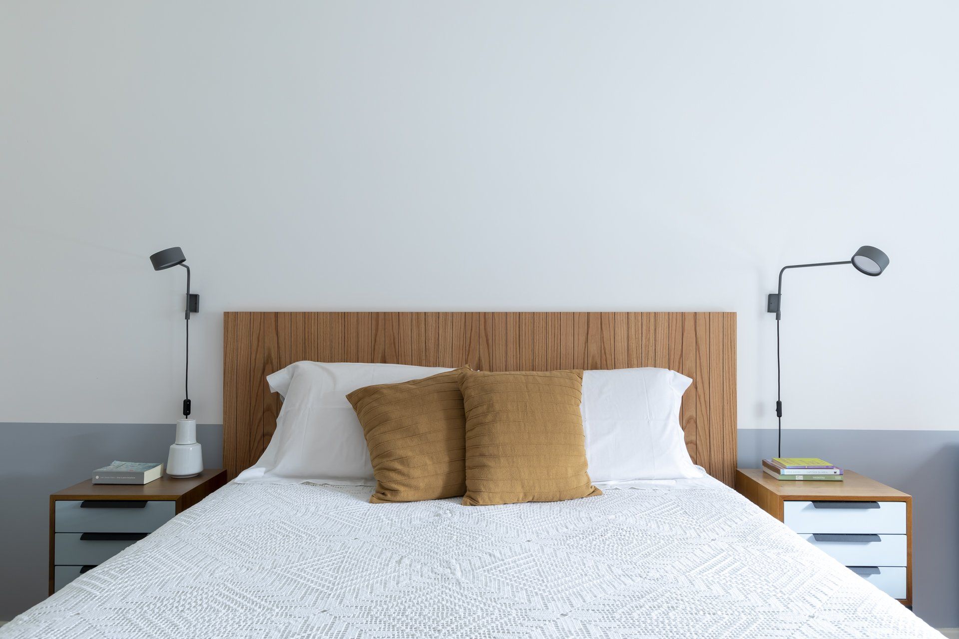 Uma cama com cabeceira de madeira e duas mesinhas de cabeceira em um quarto.