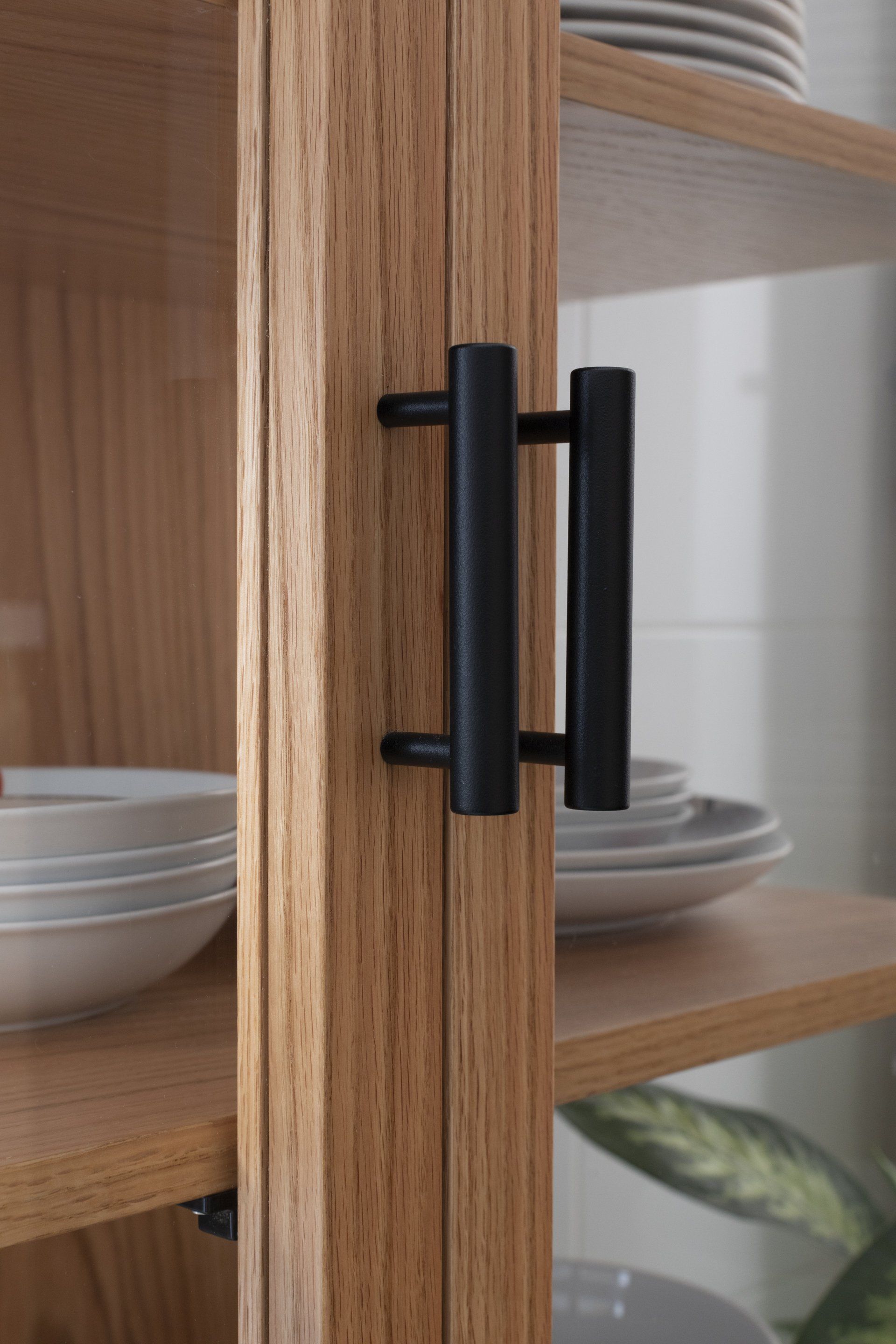 Um close de um armário de madeira com pratos e tigelas nas prateleiras.