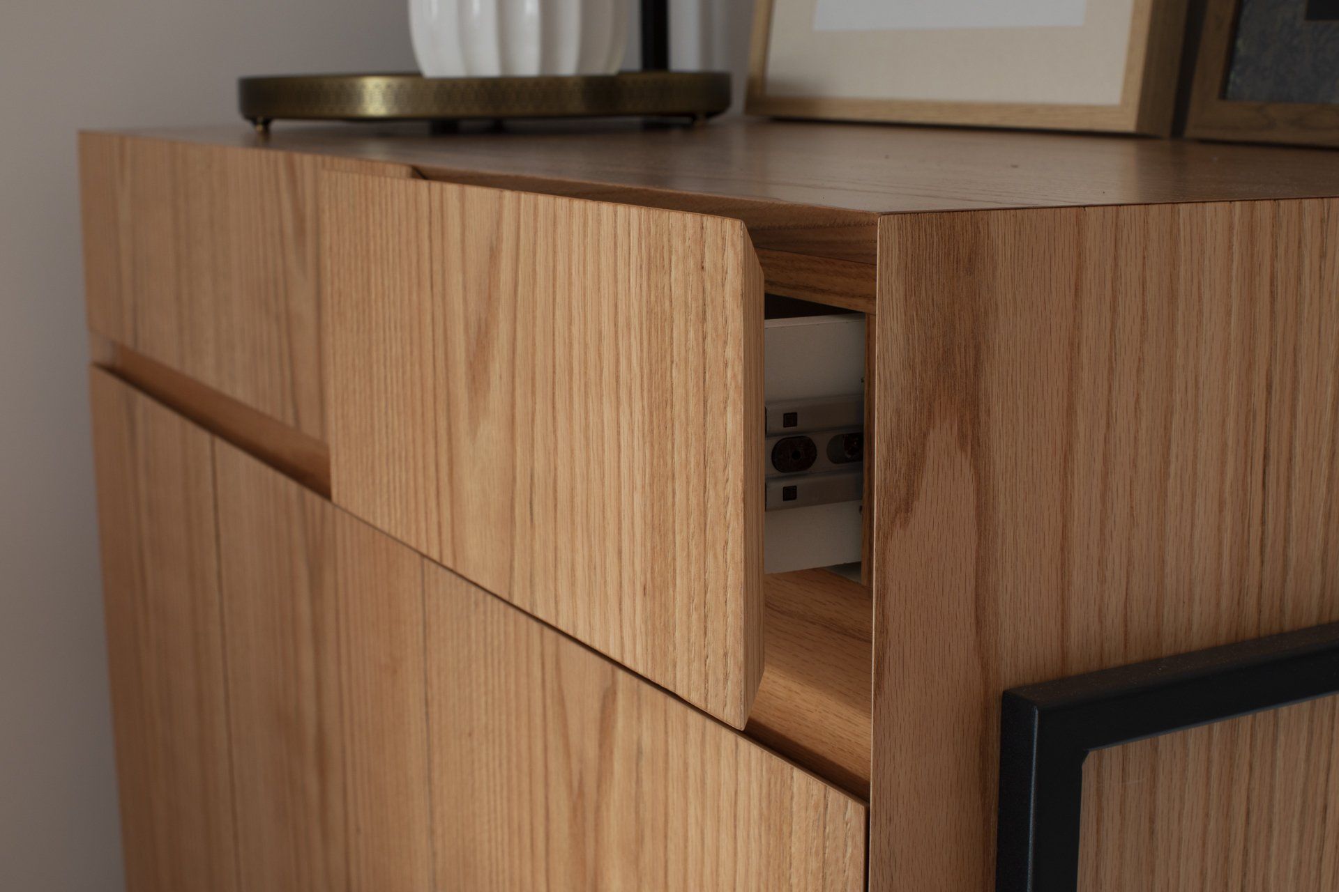 Uma cômoda de madeira com gavetas e um abajur em cima.