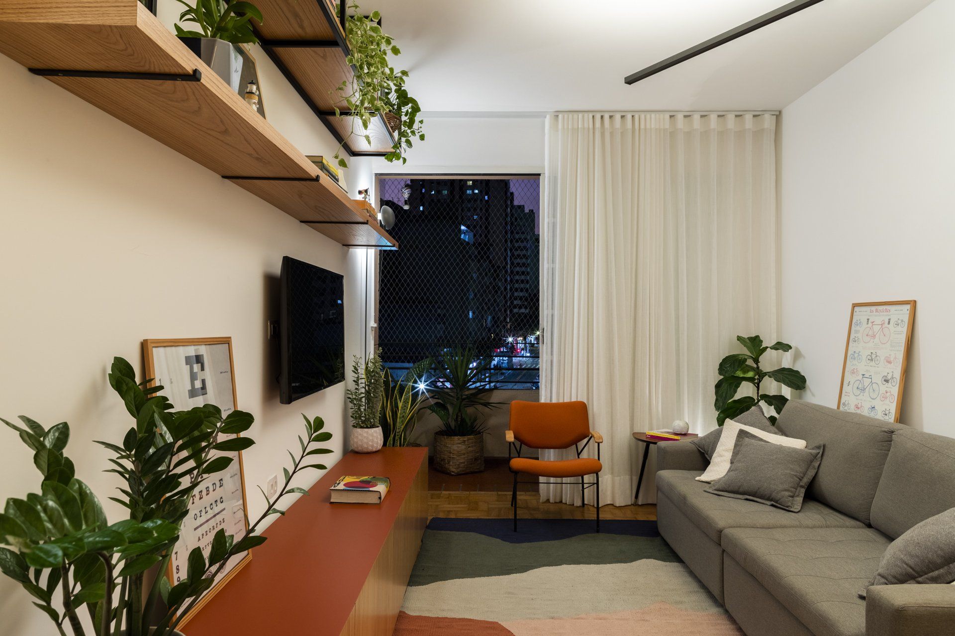 Uma sala de estar com sofá, cadeira e televisão.