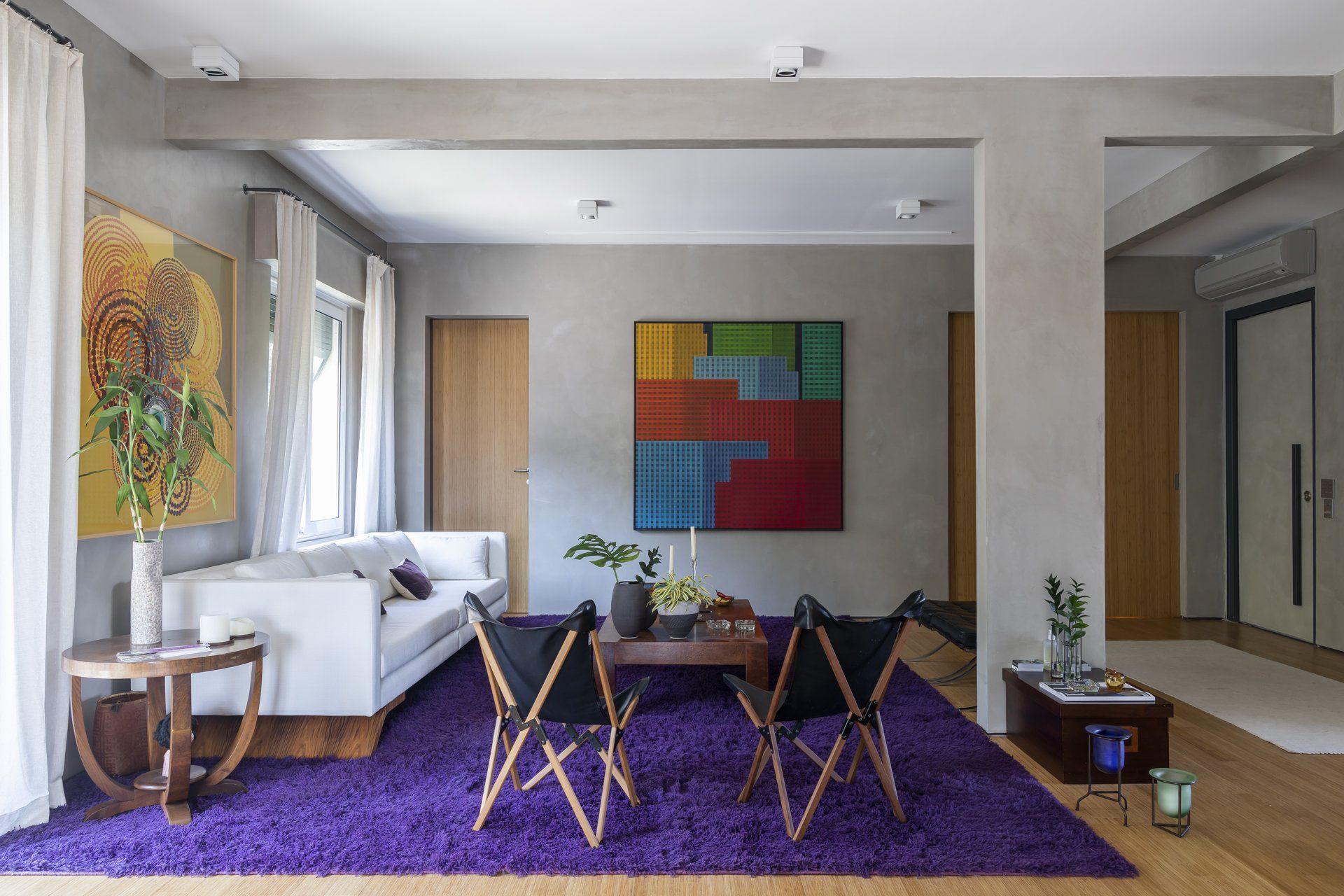 Uma sala com tapete roxo e sofá branco.