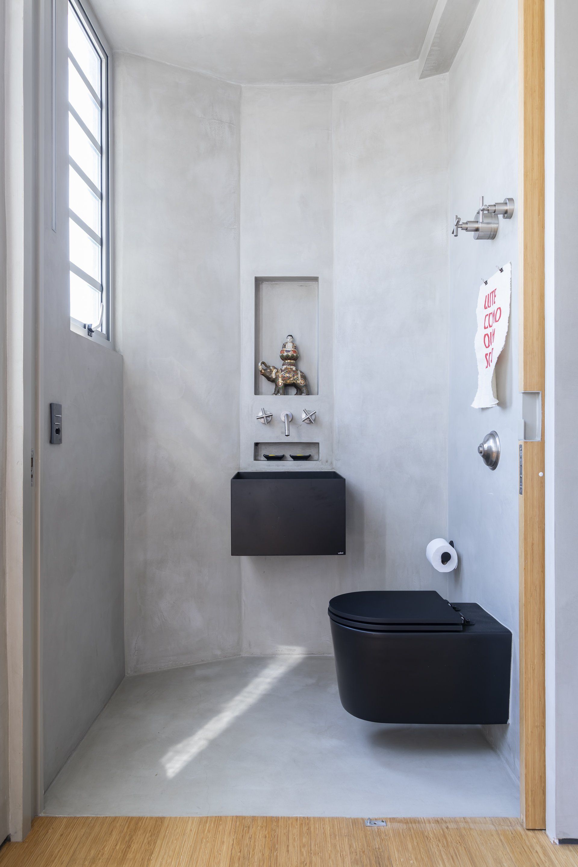 Um banheiro com vaso sanitário preto, pia e janela.