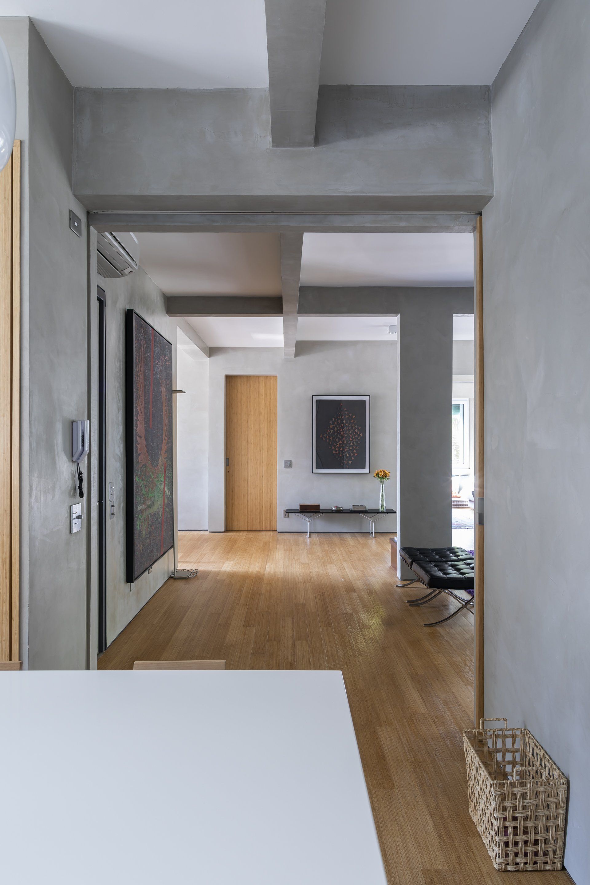 Um corredor que leva a uma sala com piso de madeira e uma mesa branca.