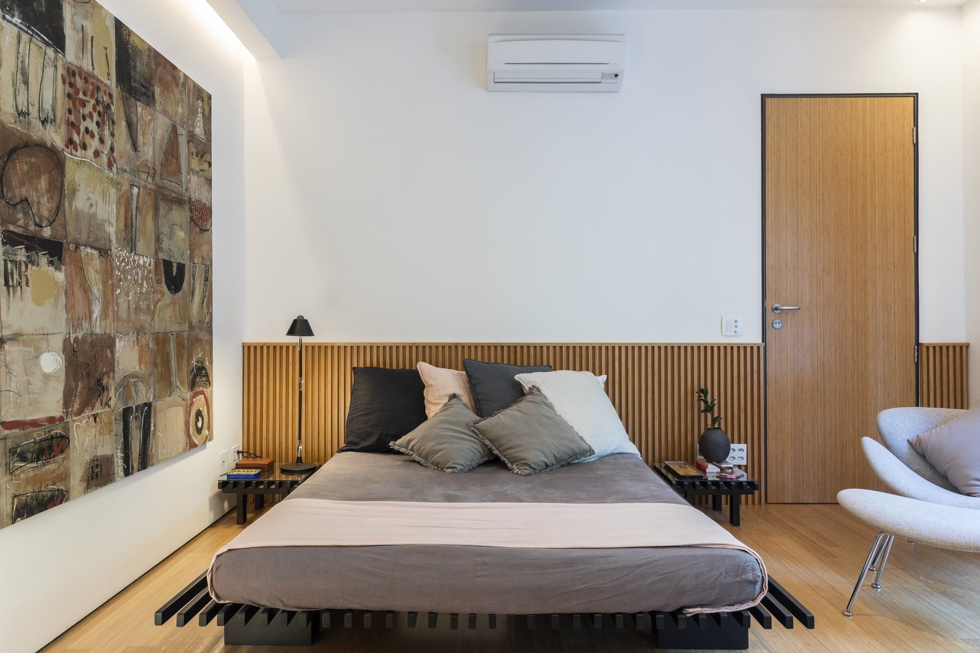 Um quarto com cama, cadeira e quadro na parede.