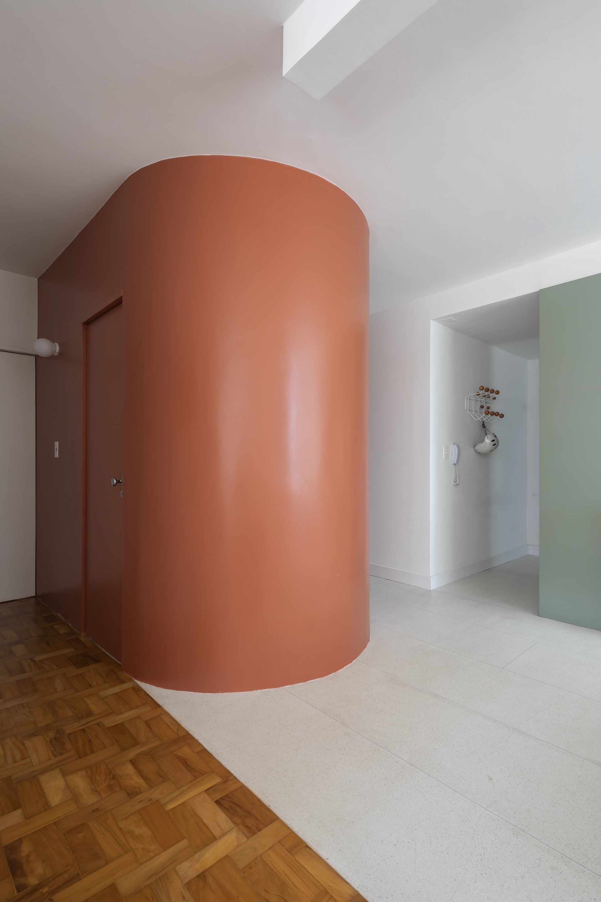 Uma sala com parede curva e piso de madeira.