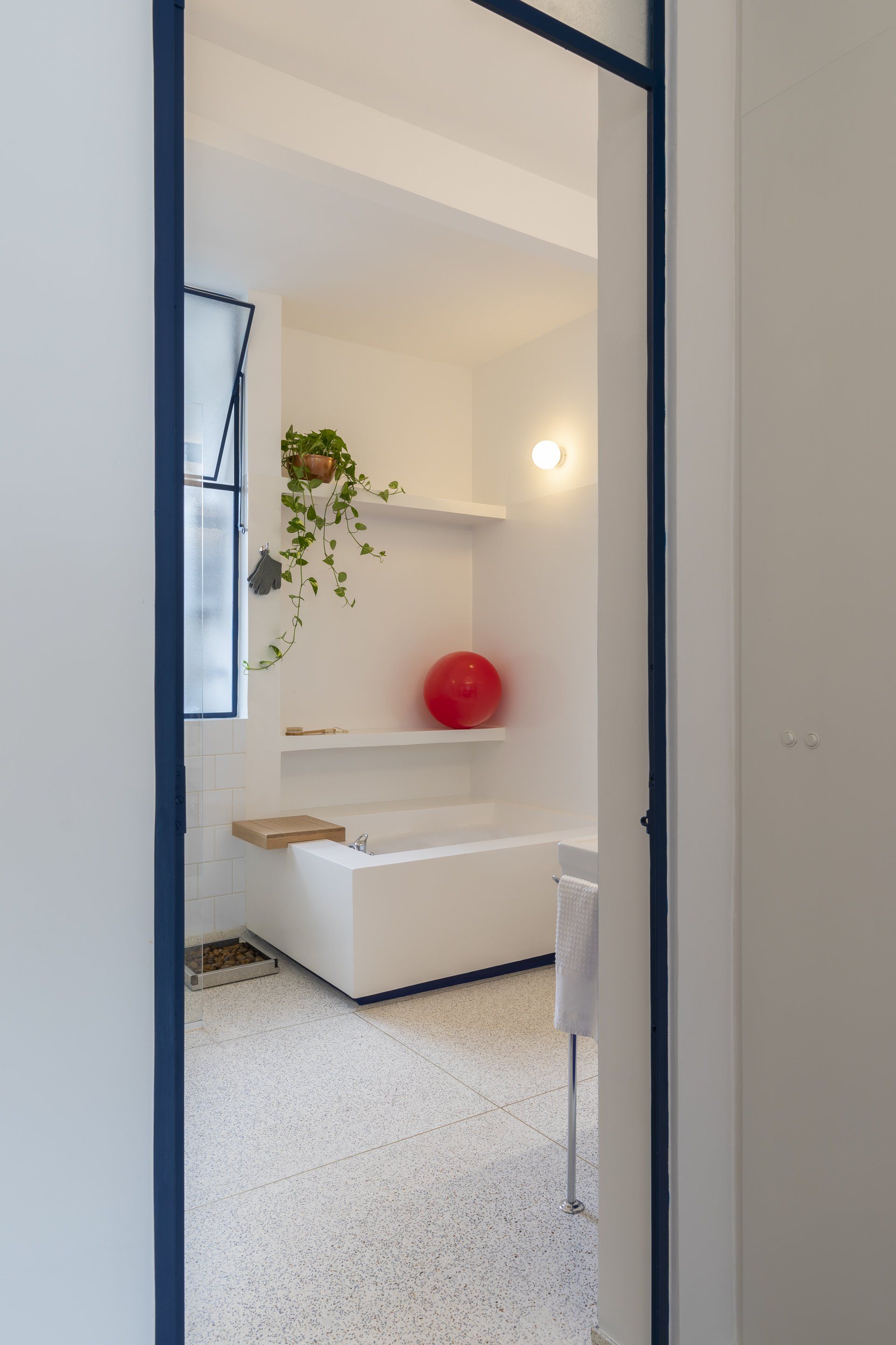 Um banheiro com banheira e uma bola vermelha na prateleira