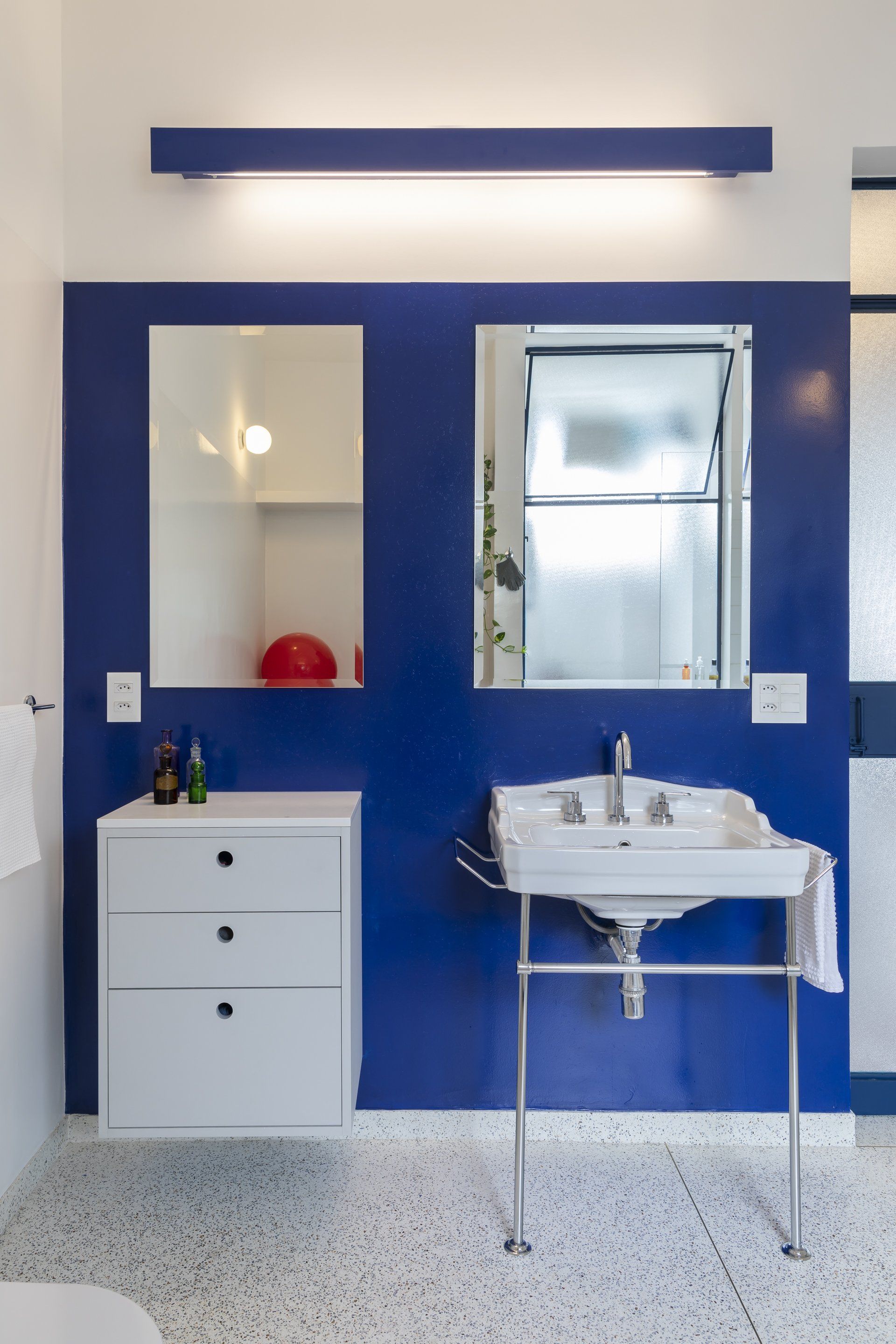 Um banheiro com paredes azuis, uma pia e dois espelhos