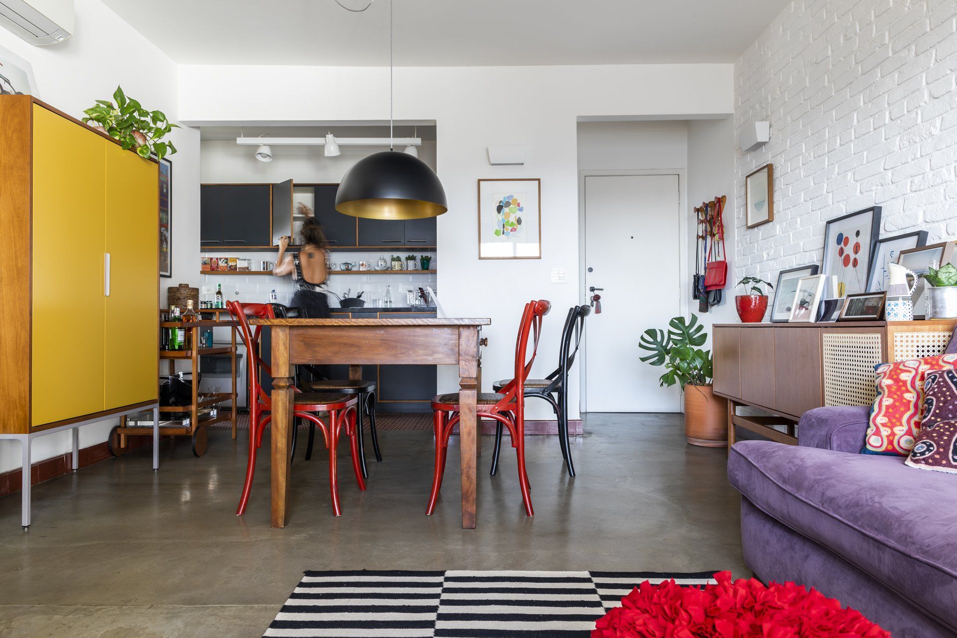 Uma sala de estar com mesa de jantar e cadeiras e um sofá roxo.