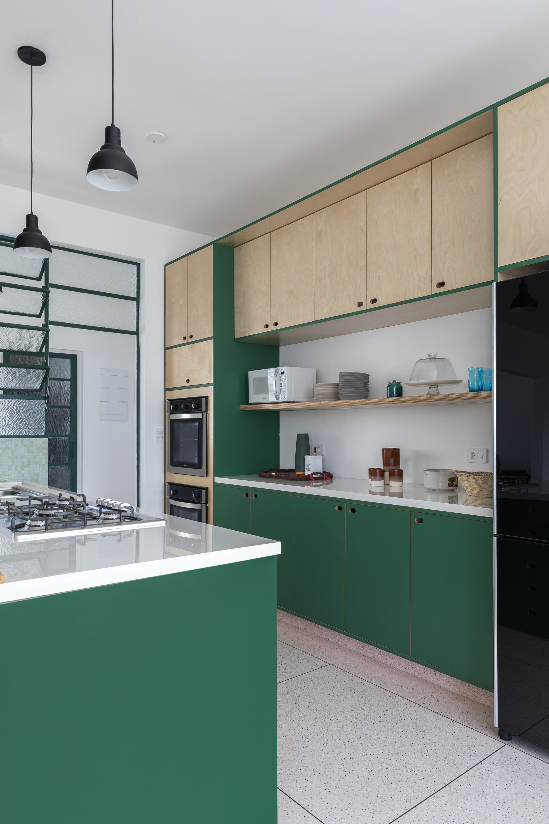 Uma cozinha com armários verdes e uma geladeira preta