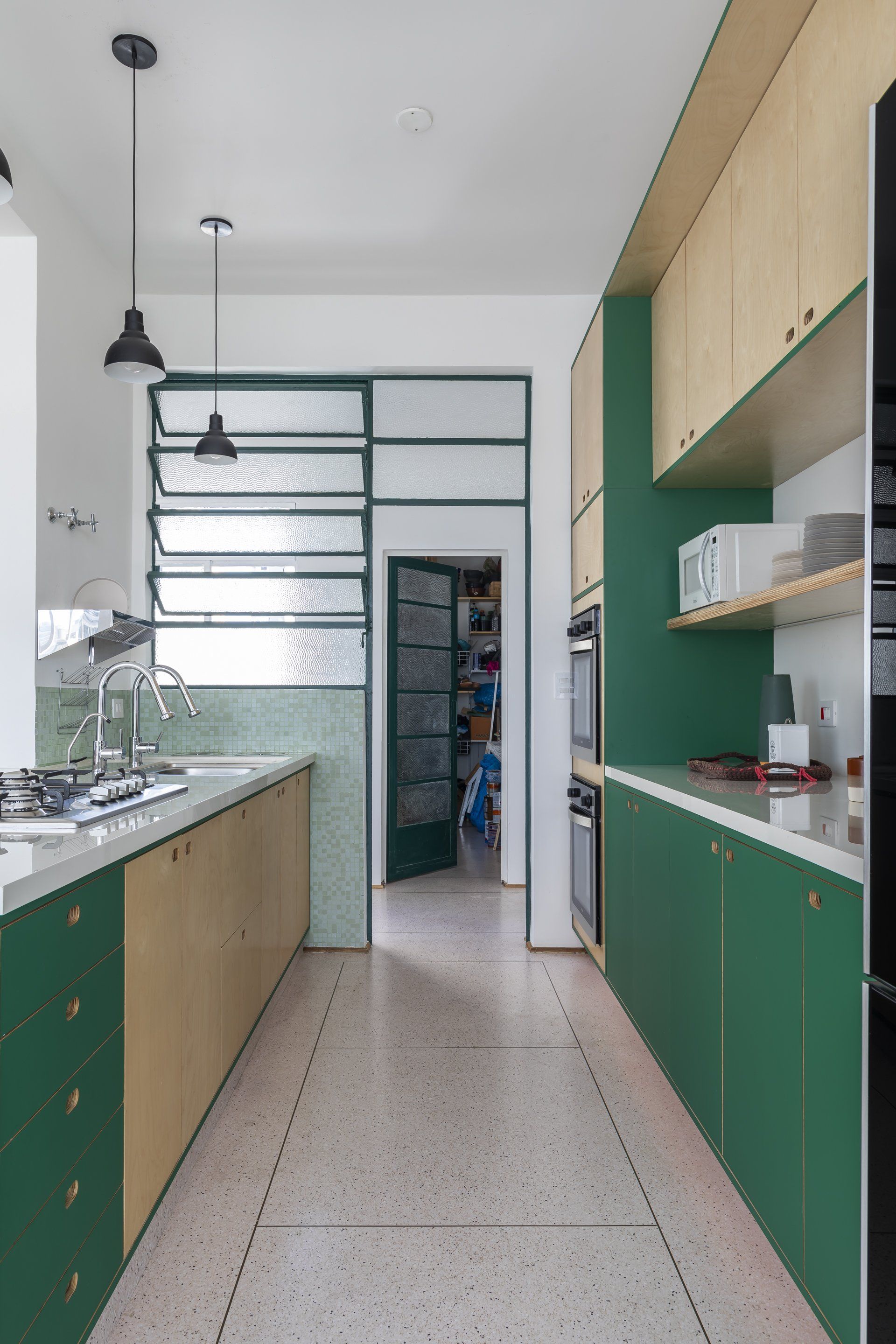 Uma cozinha com armários verdes e piso de cerâmica rosa.