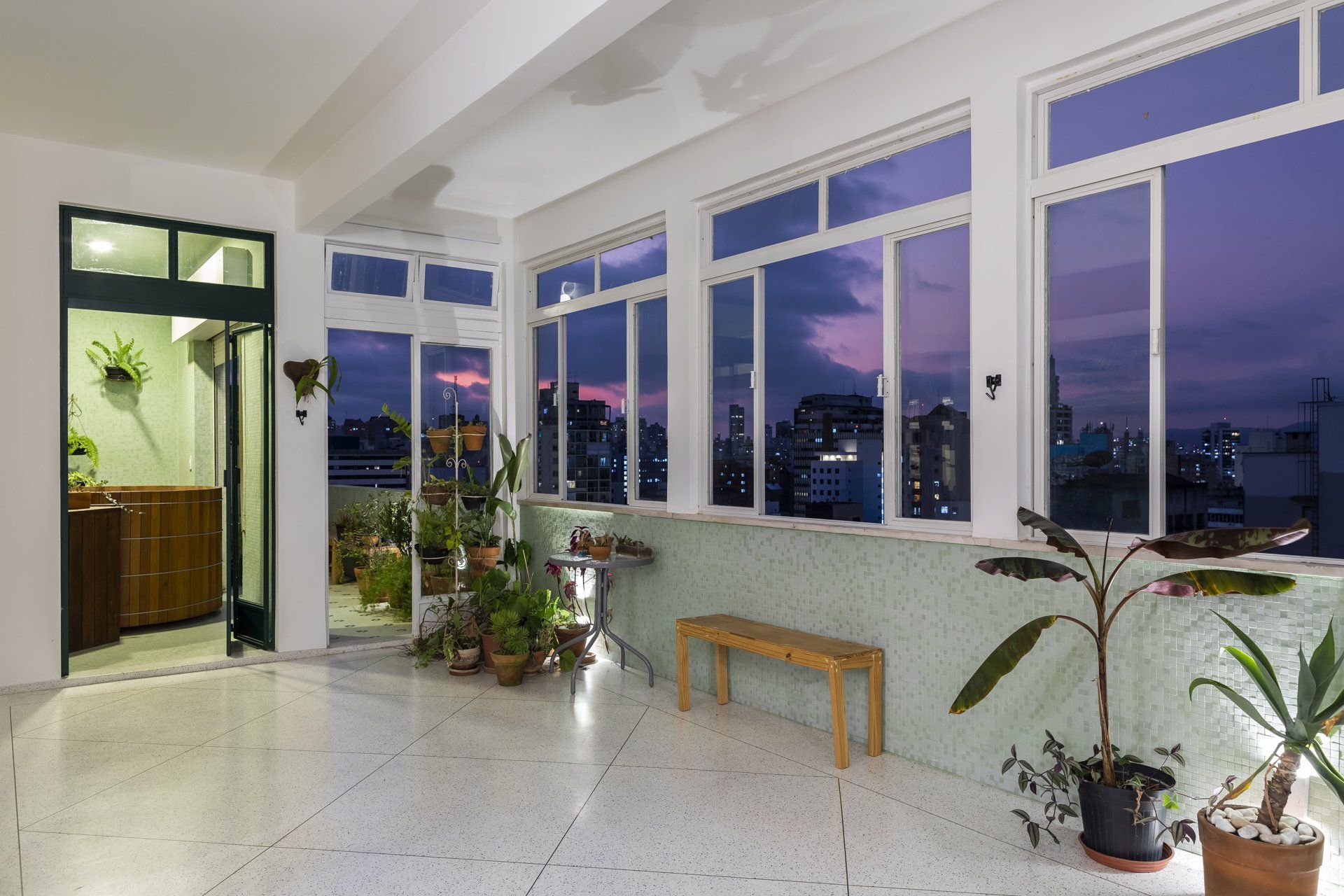 Uma sala grande com muitas janelas e vasos de plantas
